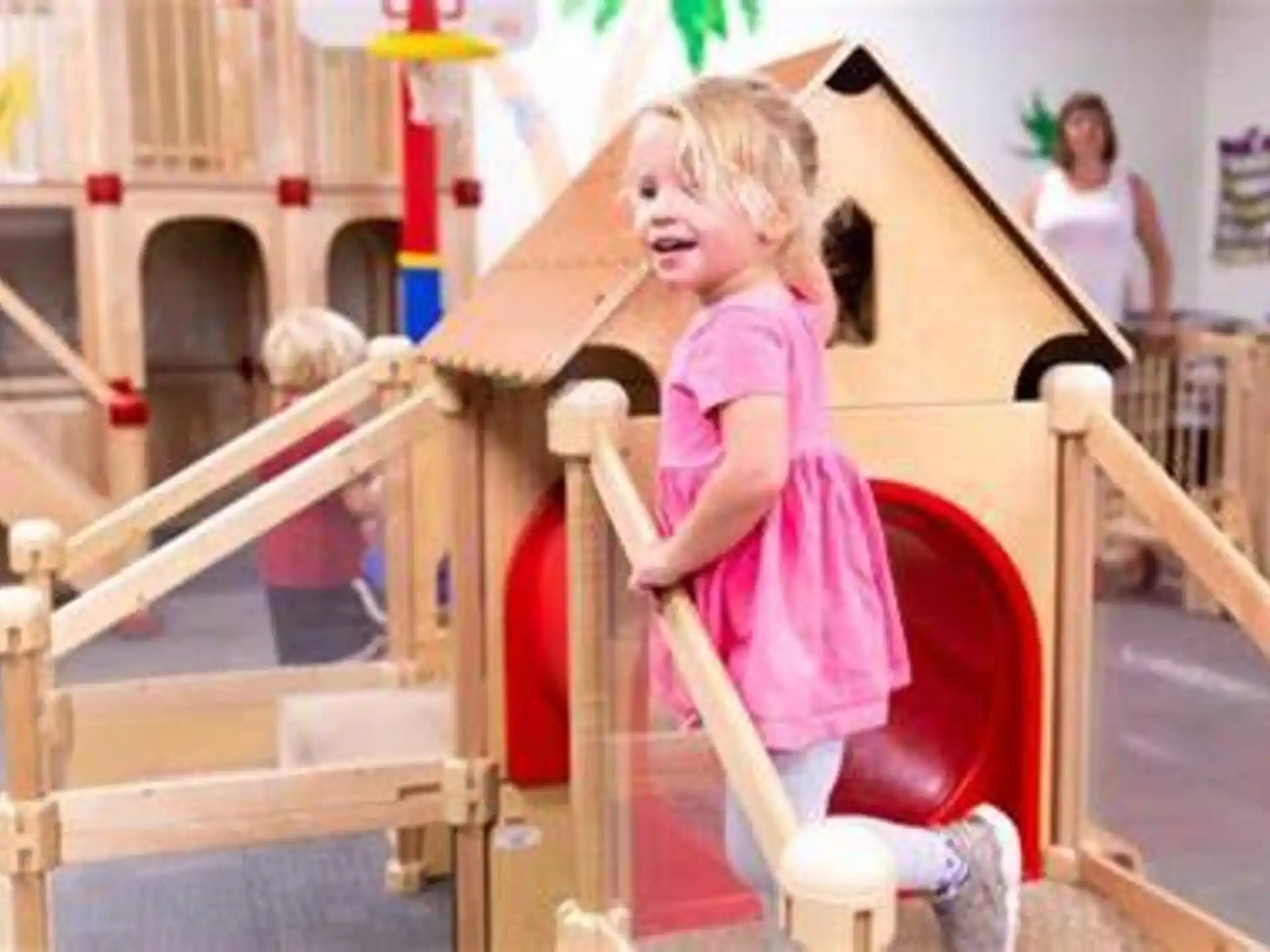 a girl in a pink dress on a play set