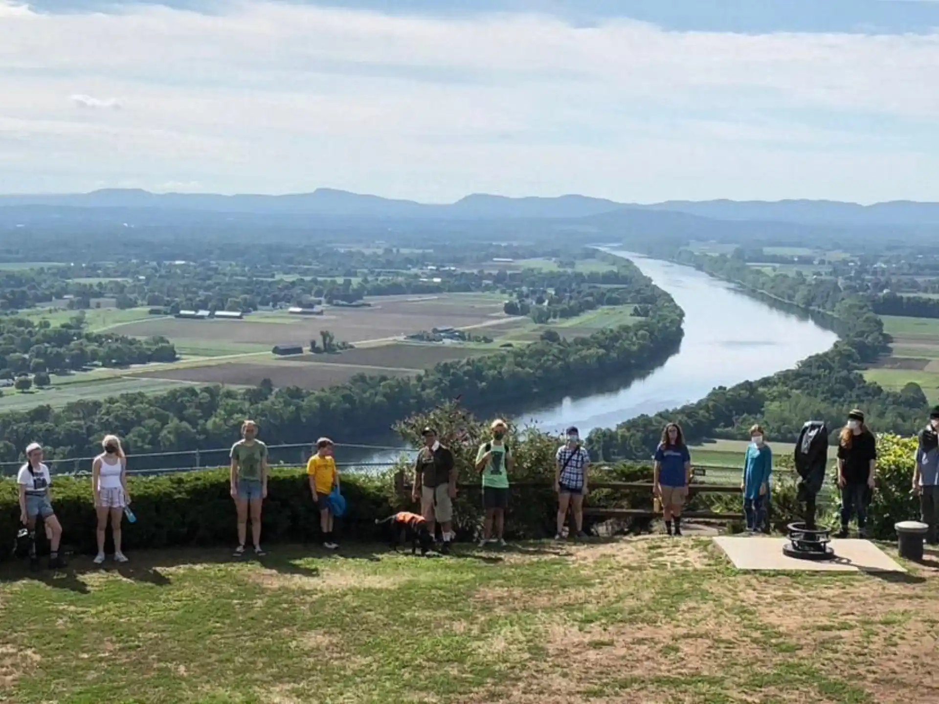 a group of people standing on a hill overlooking a river
