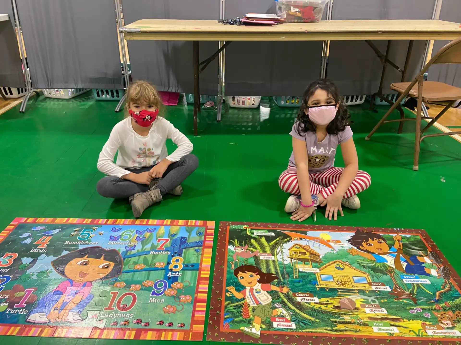 a couple of children sitting on the floor with a table and chairs