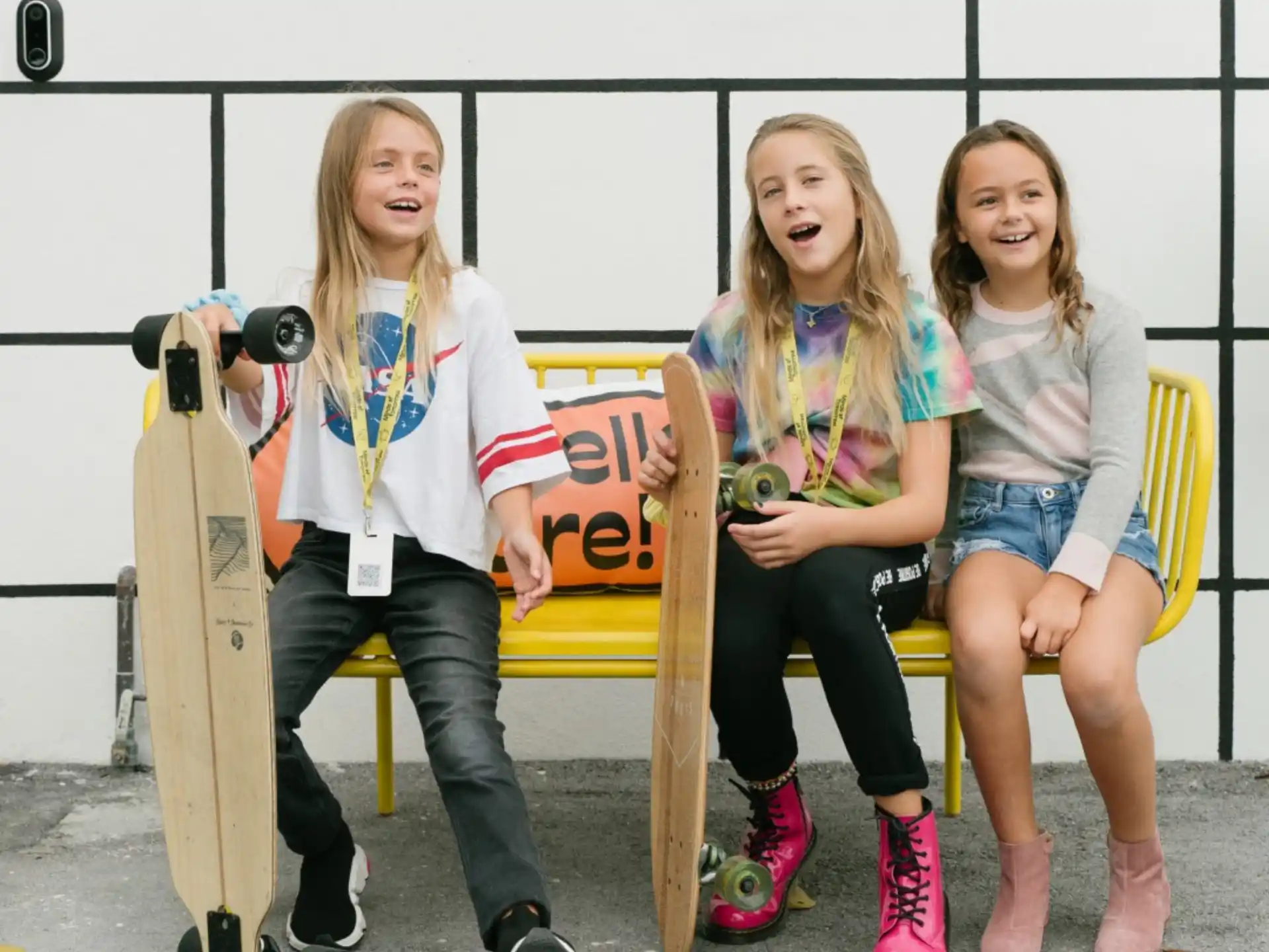 a group of girls sitting on a bench with a skateboard