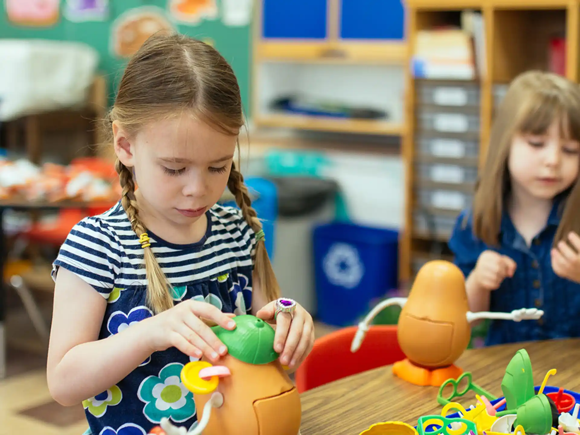 a couple of young girls playing with toys in a classroom