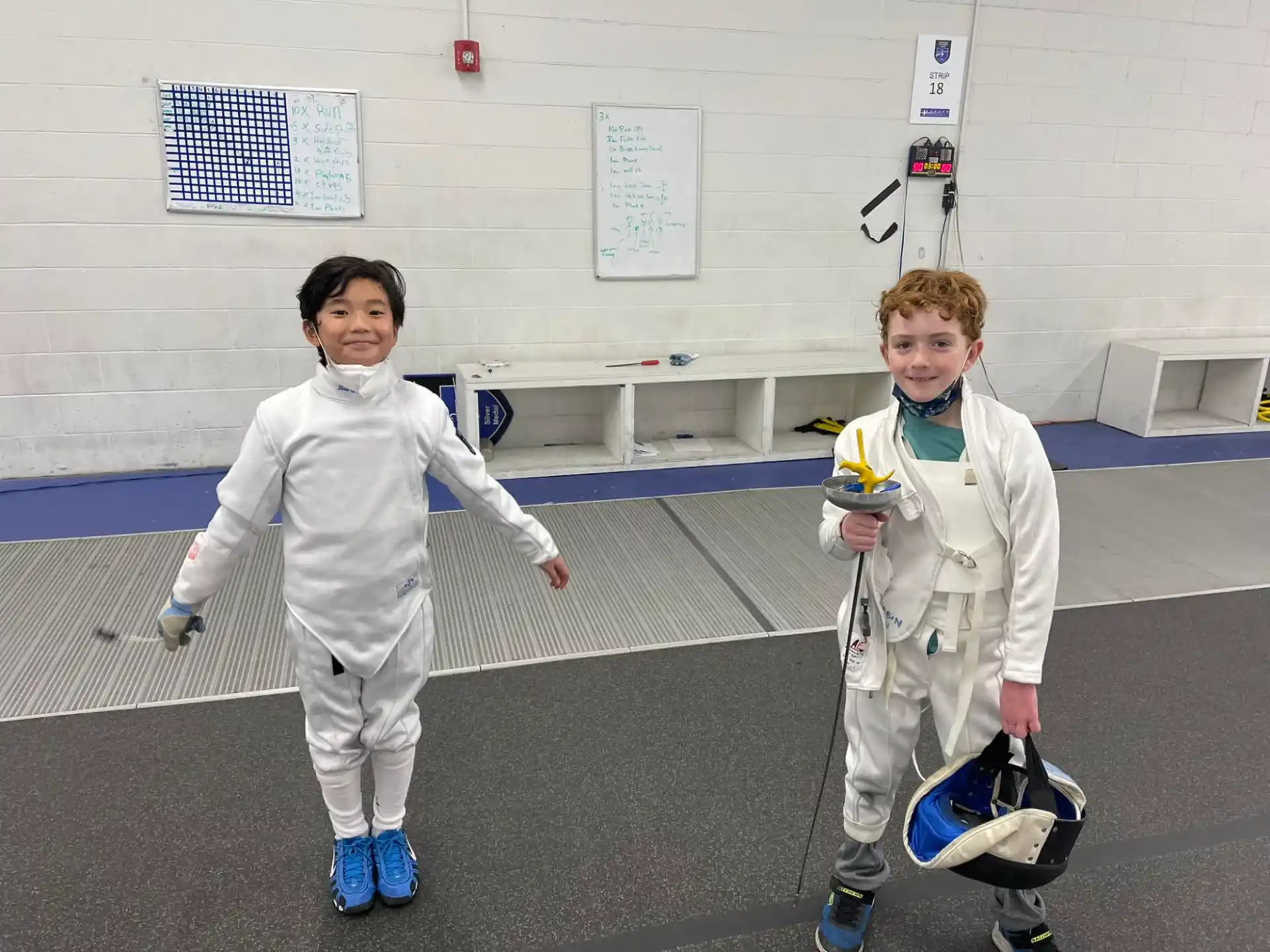 a couple of kids wearing white uniforms and holding helmets