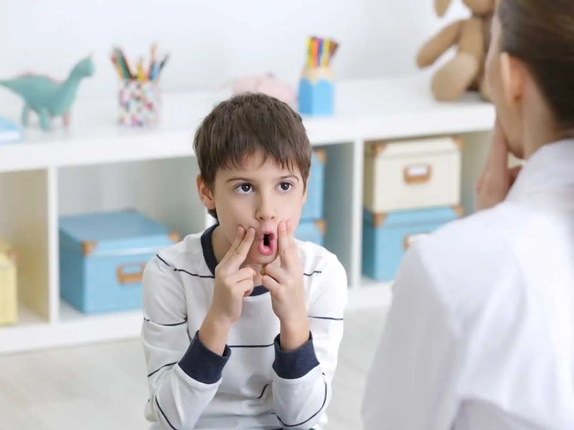 a boy with the hands on the face and a person in the background