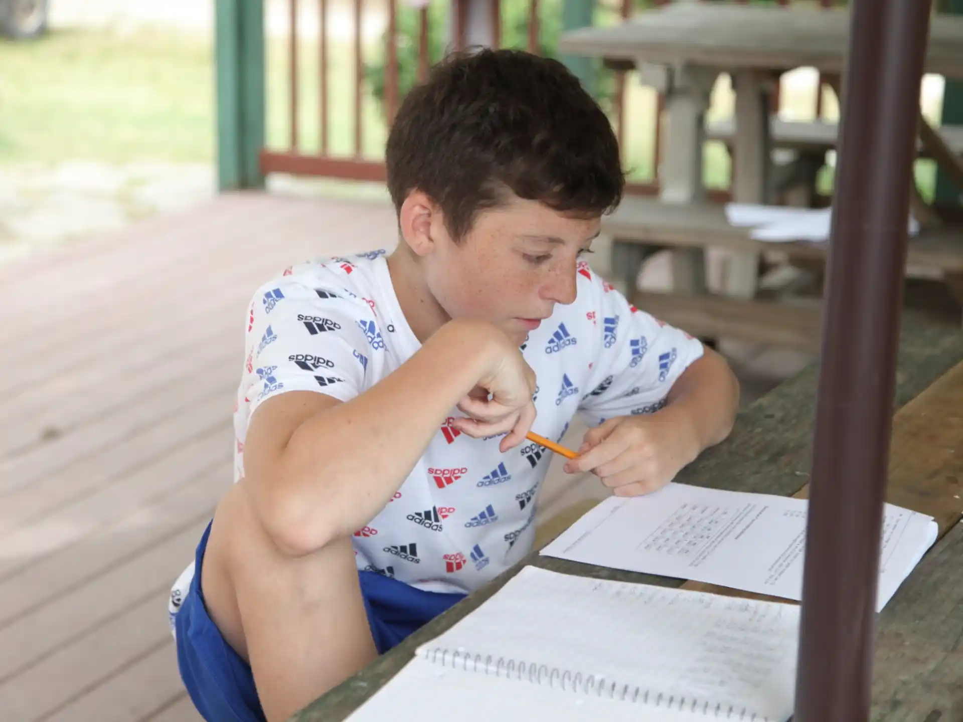 a young man sitting at a table writing on a piece of paper