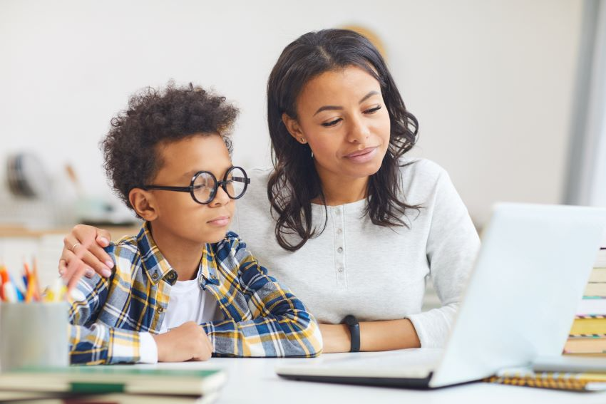 a person and a boy looking at a laptop