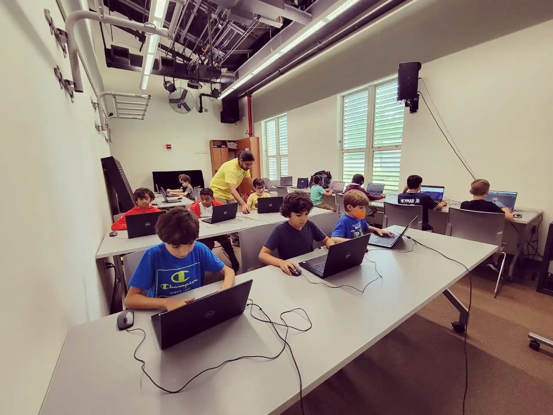 a group of people sitting at tables with laptops