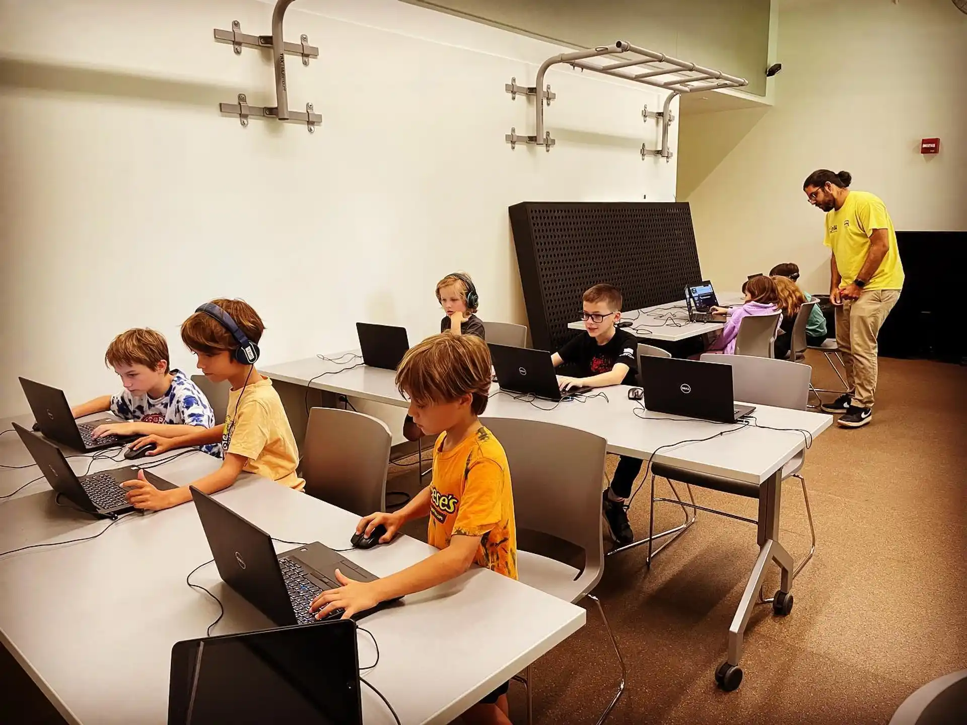 a group of people sitting at tables with laptops