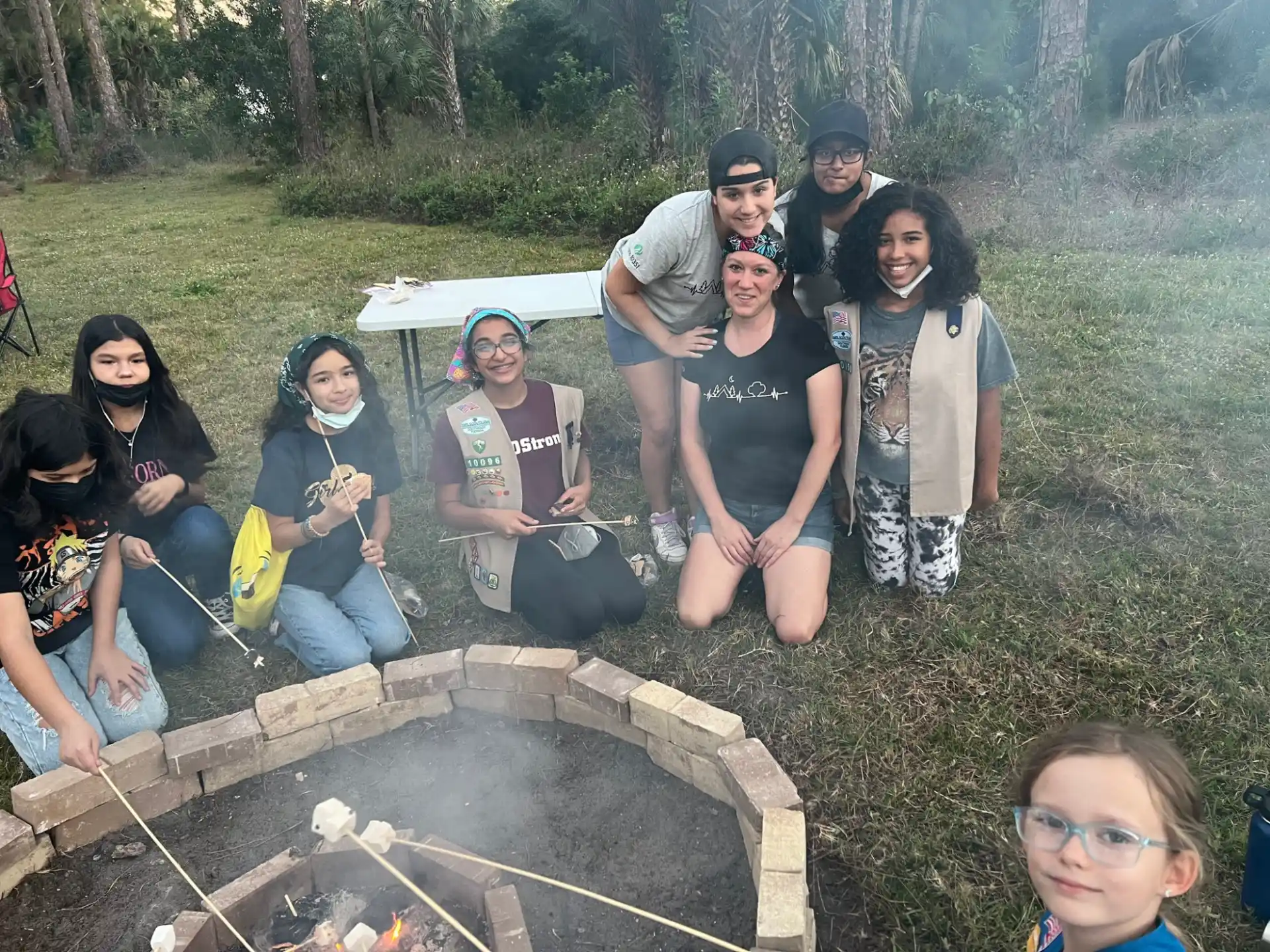 a group of people posing for a photo next to a campfire