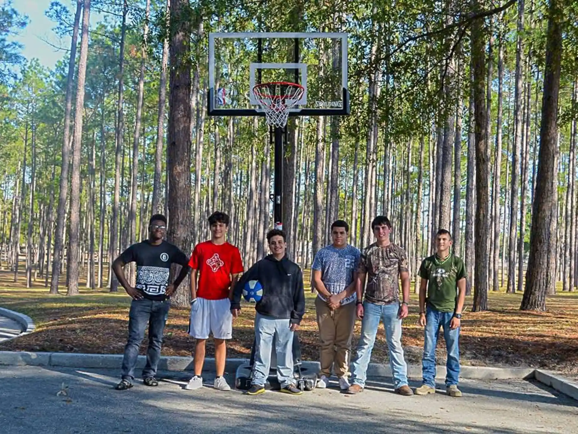 a group of men standing in front of a basketball hoop in the woods