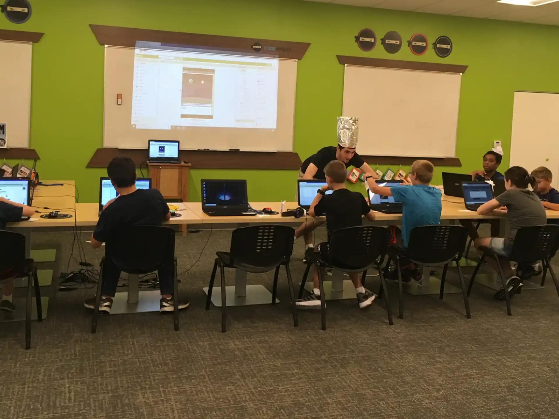 a group of people sitting at a table with computers