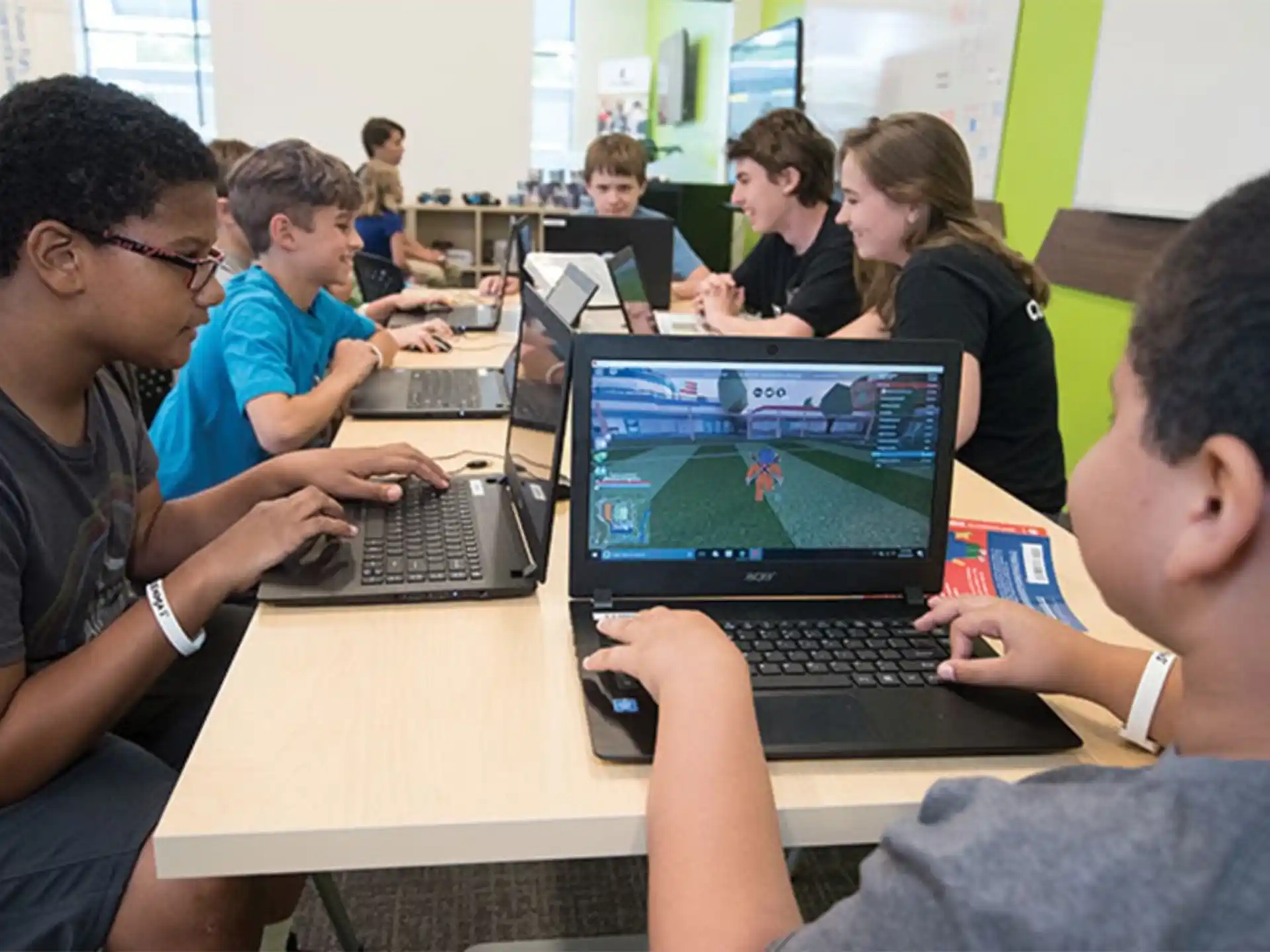 a group of people sitting at a table with laptops