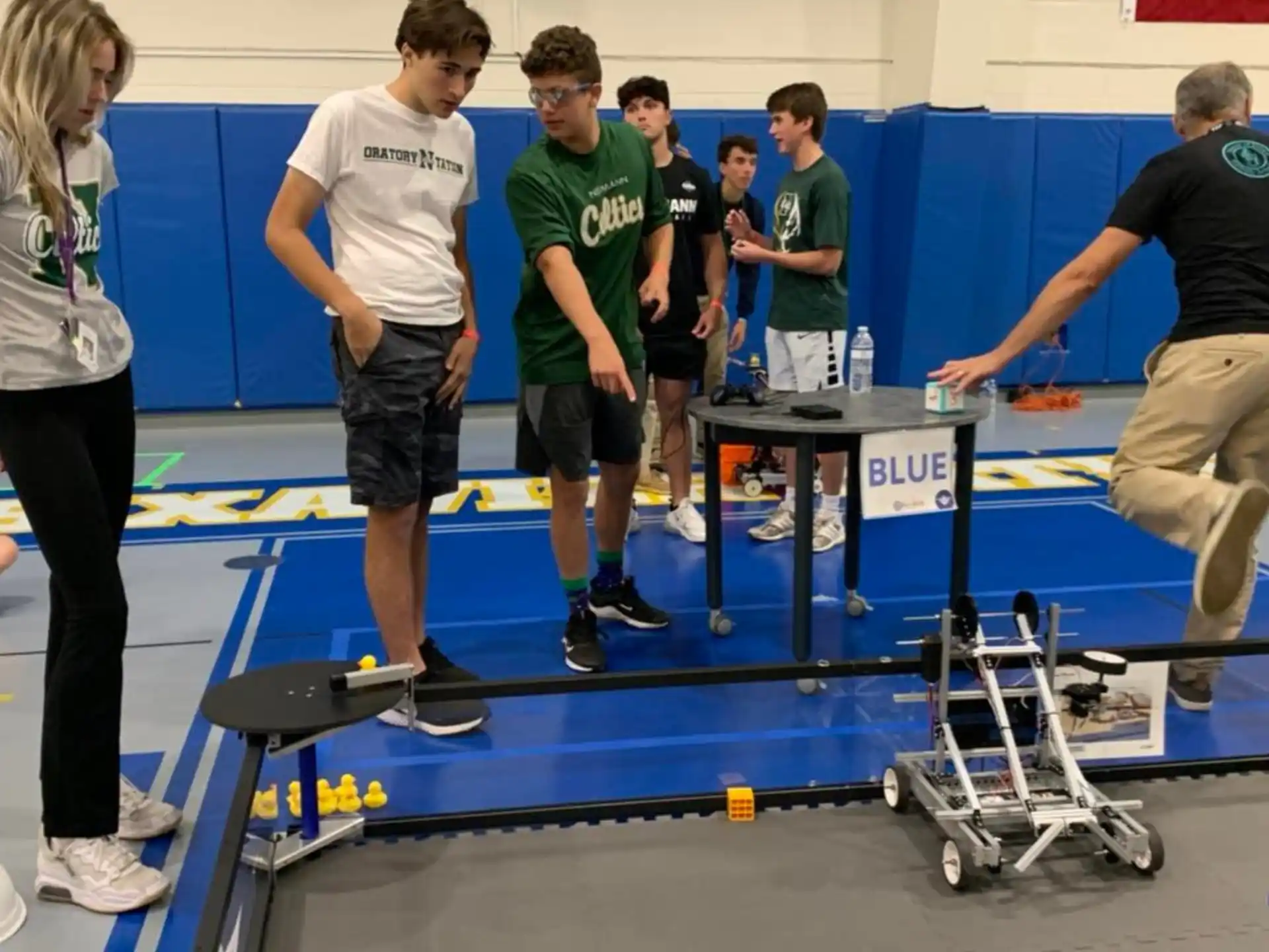a group of people standing around a table with a blue table and a flag
