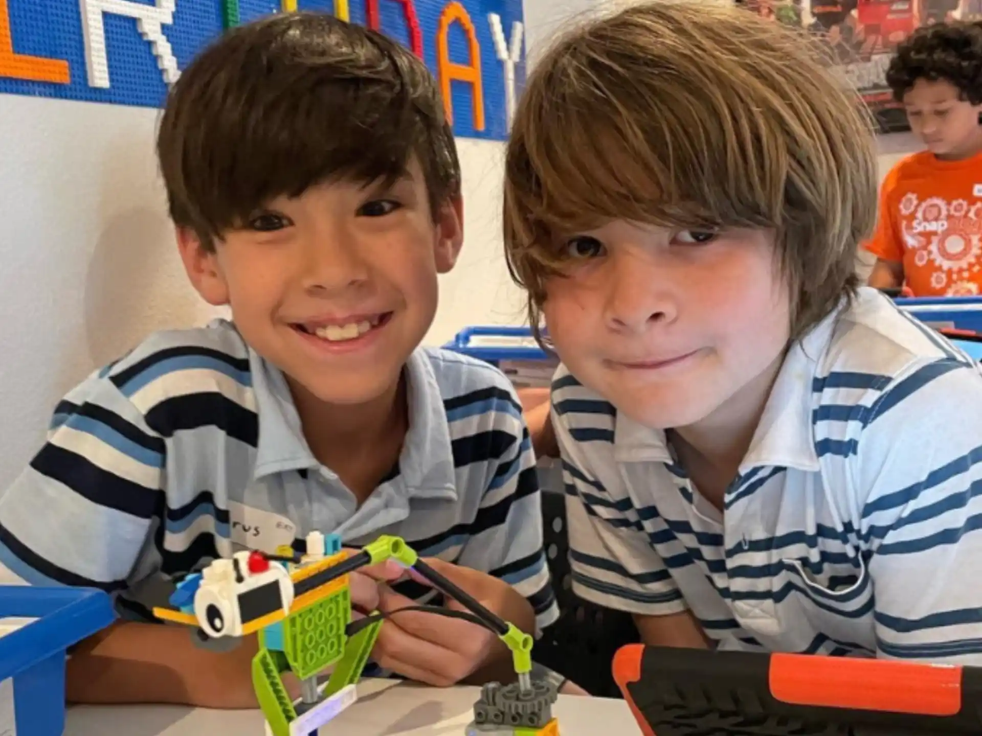 a couple of boys sitting at a table with a toy train