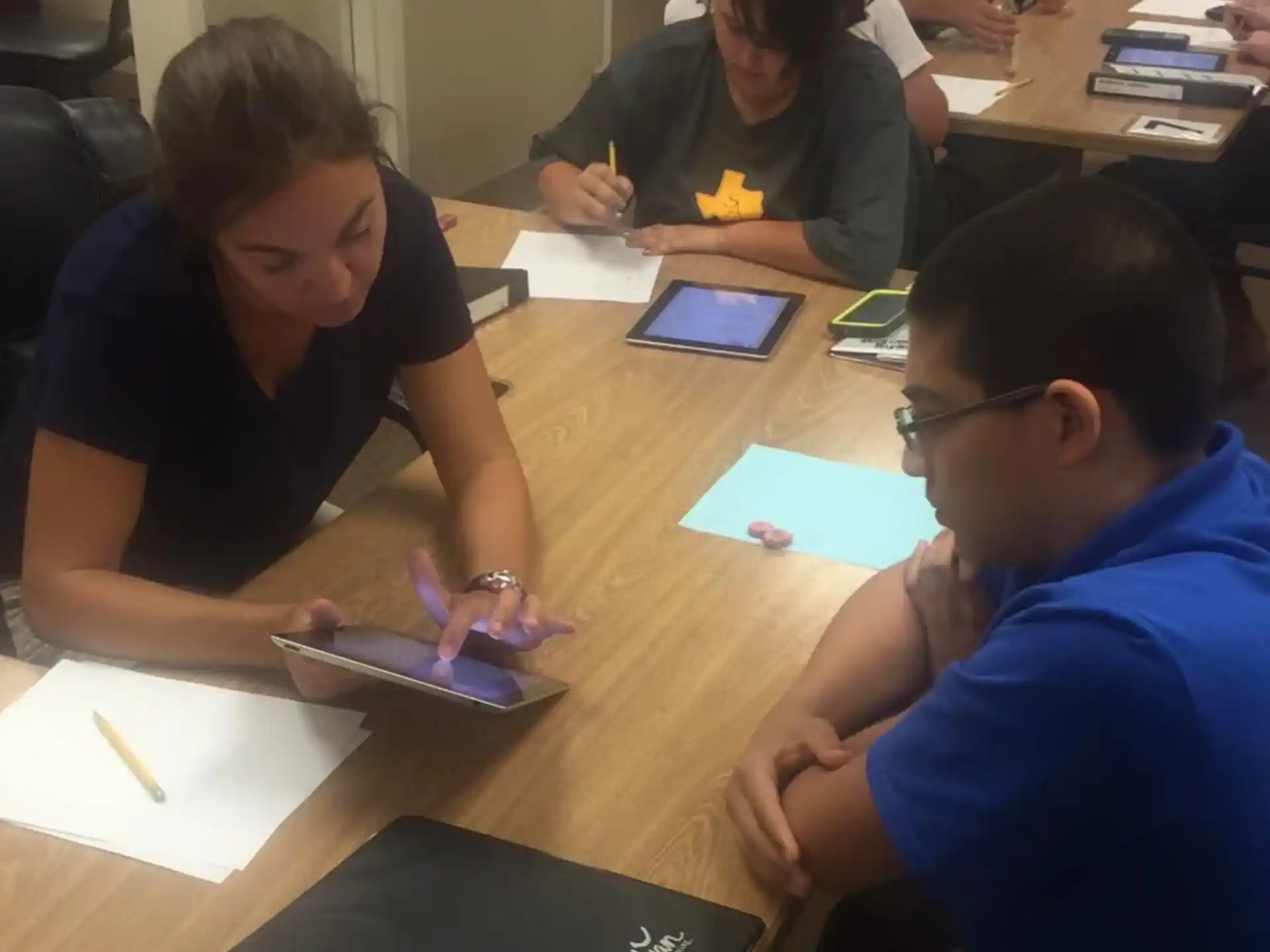 a group of people sitting at a table looking at a tablet