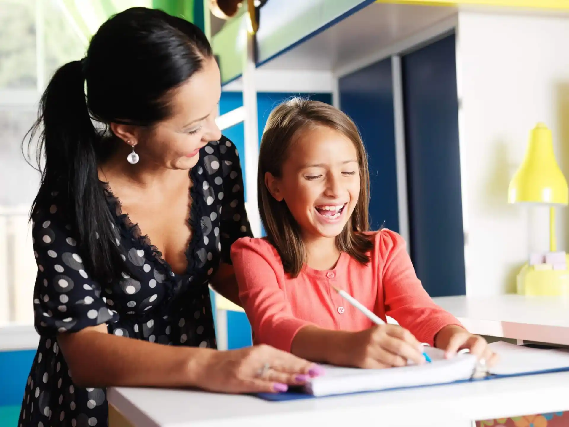 a woman showing a girl something on the paper