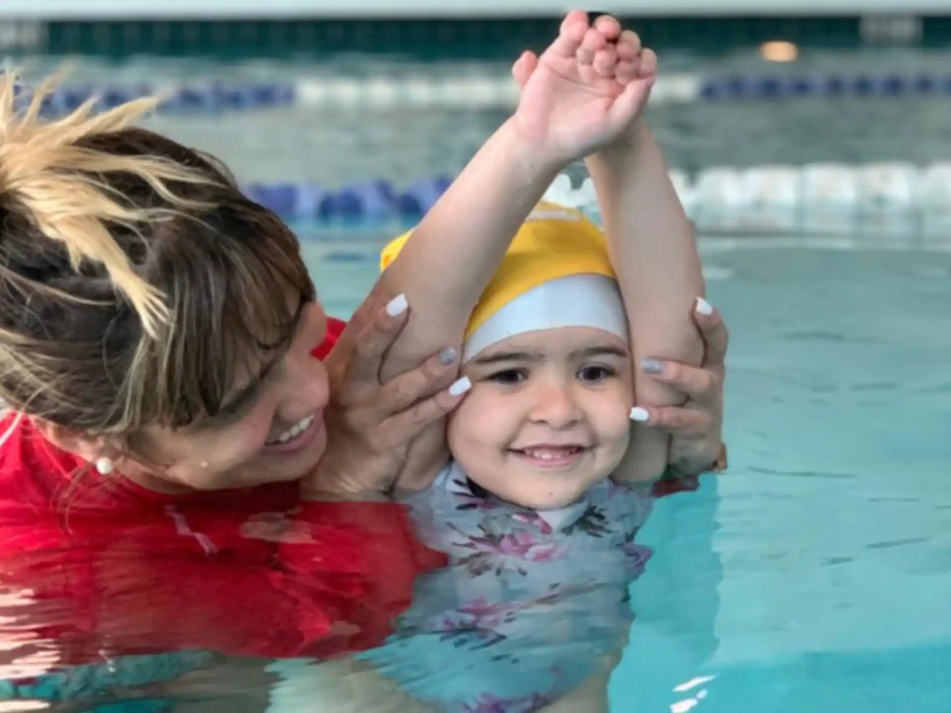 a person holding a baby in a pool
