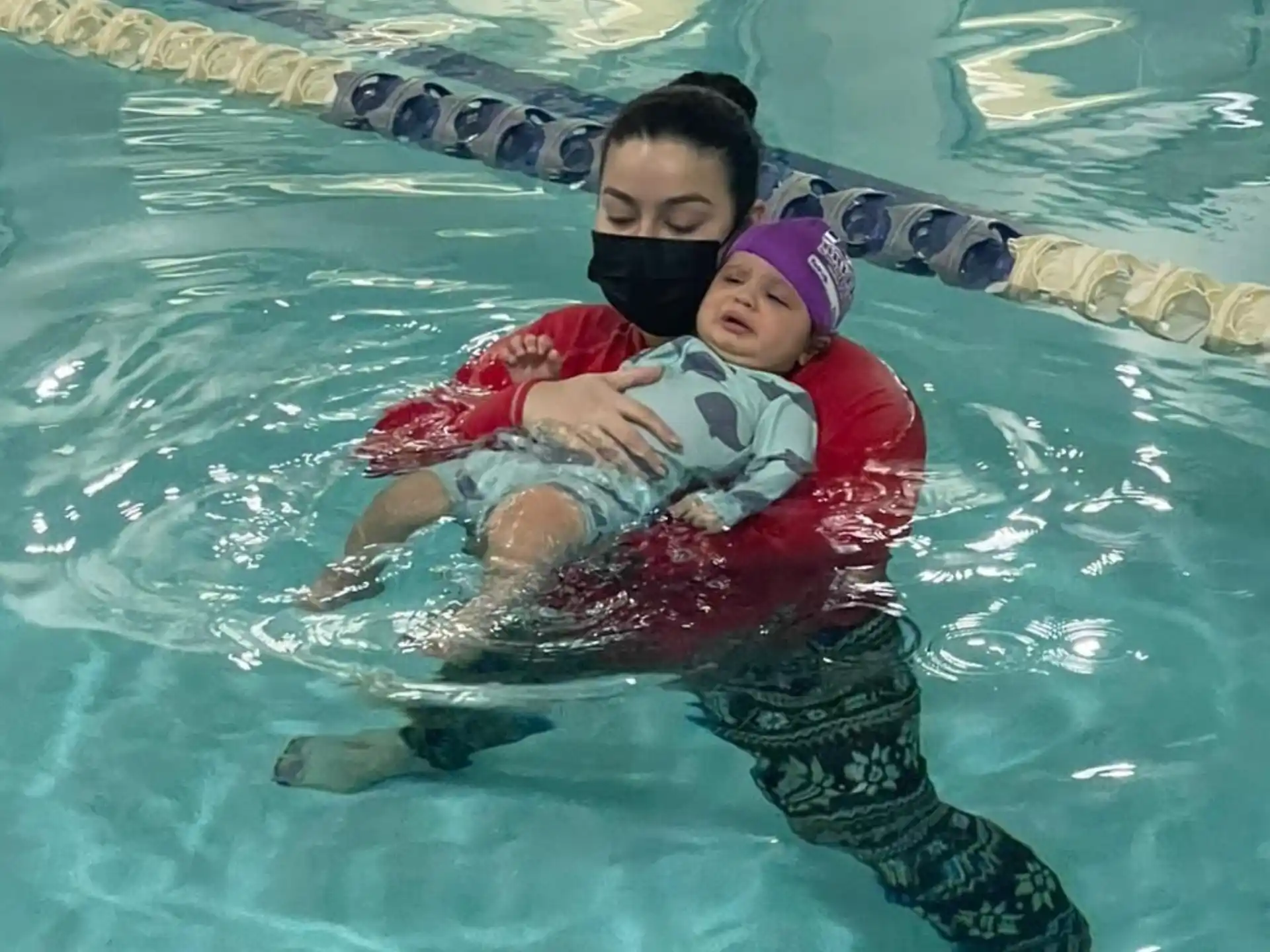 a person holding a baby in a pool