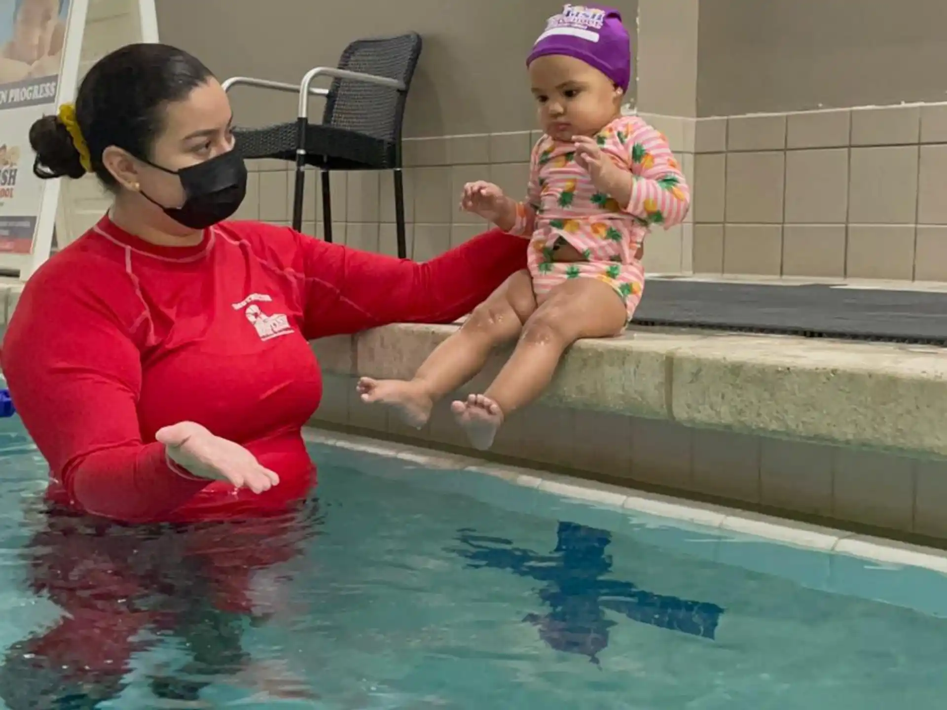 a person holding a baby in a pool