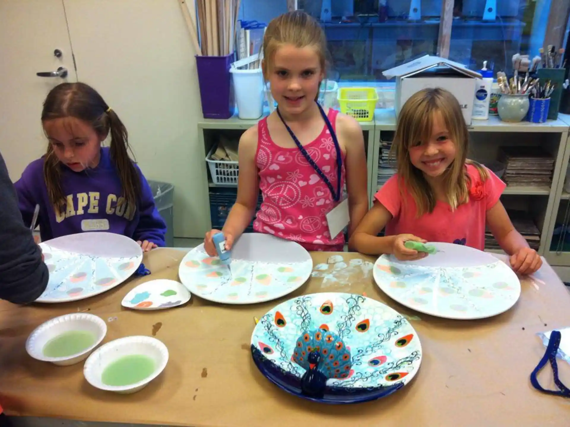 a group of children sitting at a table with plates of food