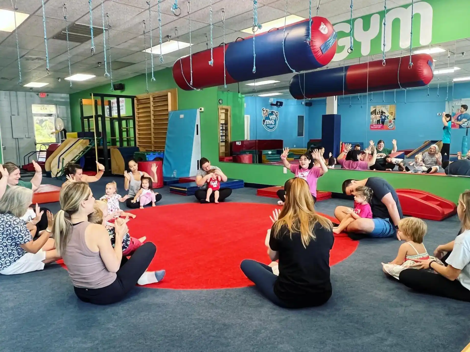 a group of children sitting on the floor in a room with balloons