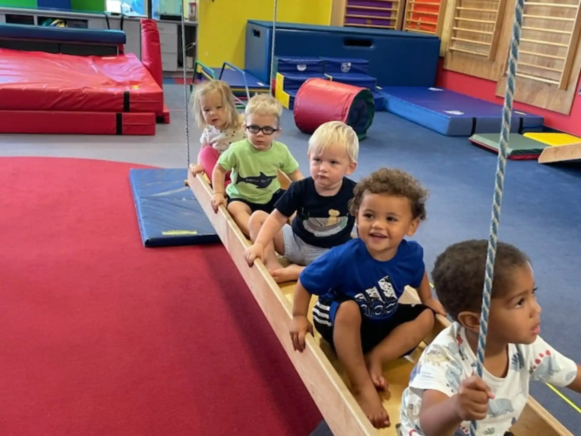 a group of kids sitting on a mat in a gym