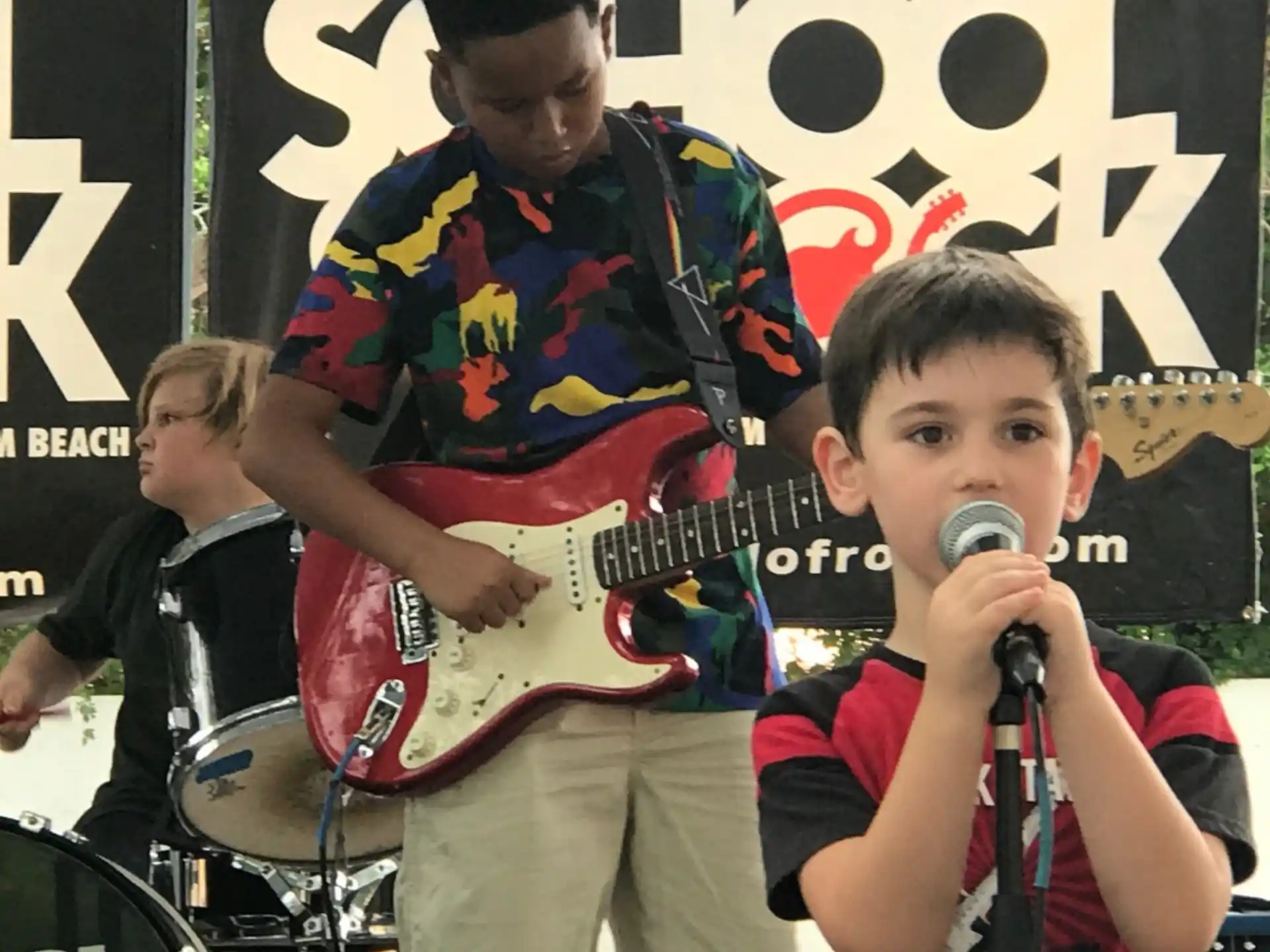 a boy playing a guitar next to a person playing drums