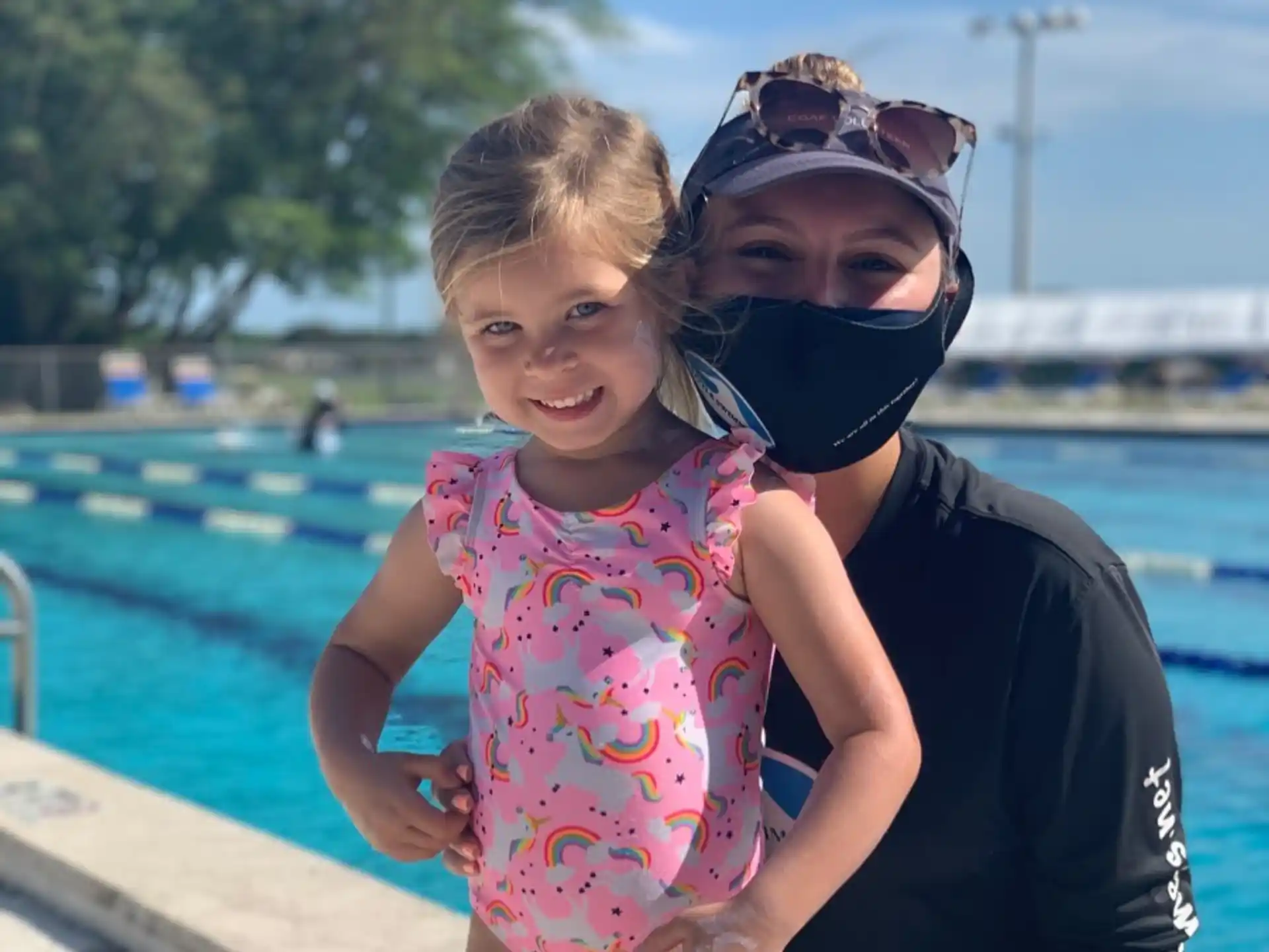 a person and a child posing for the camera by a pool