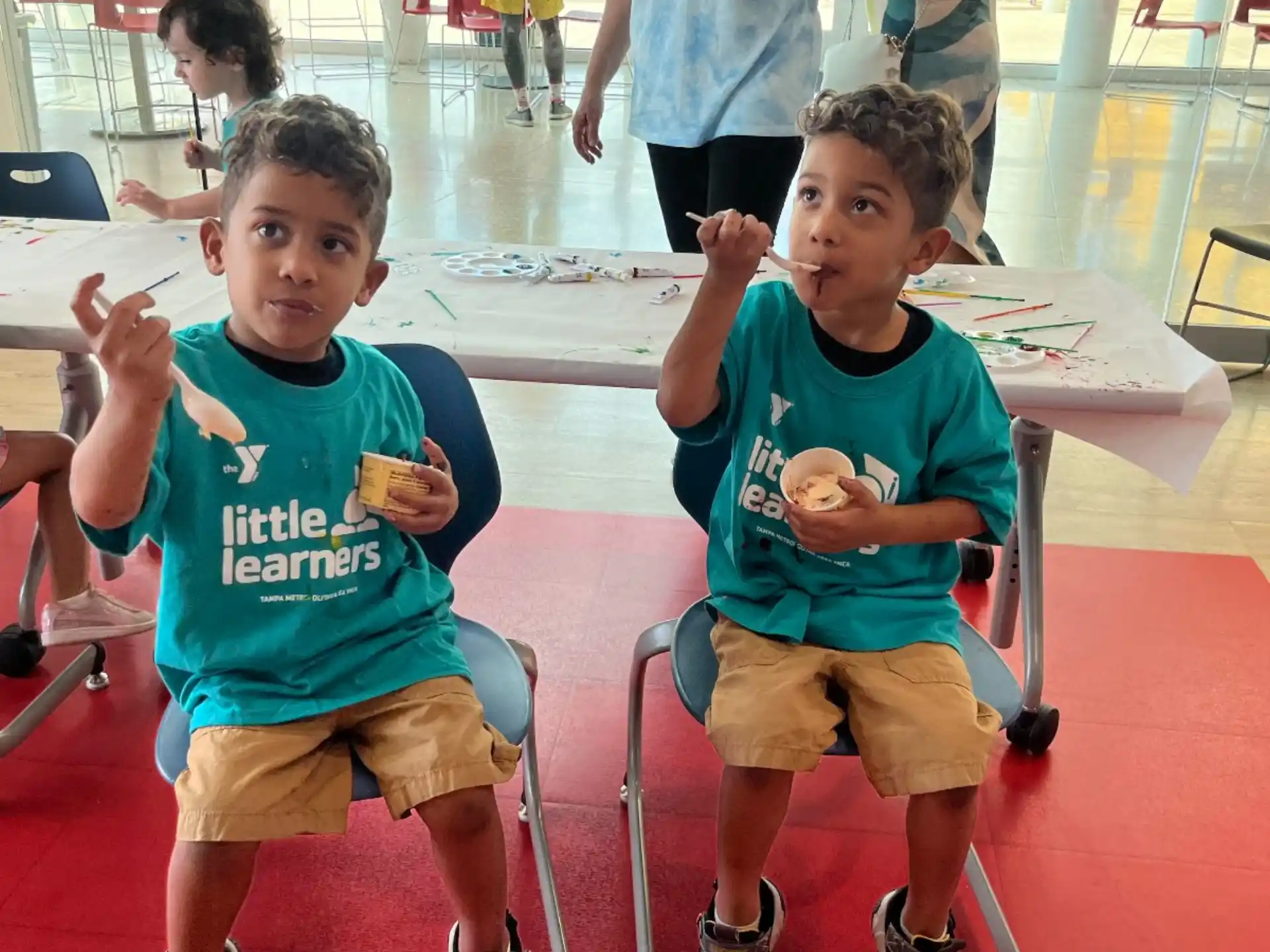 a couple of boys sitting in chairs eating ice cream