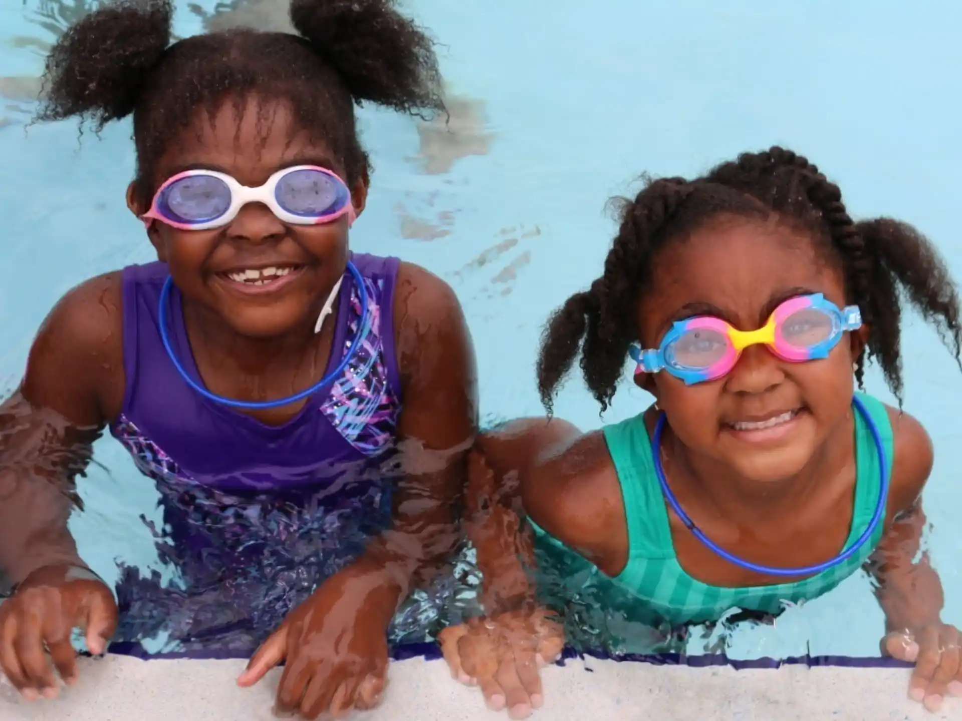 a couple of kids wearing swimsuits and goggles on a beach
