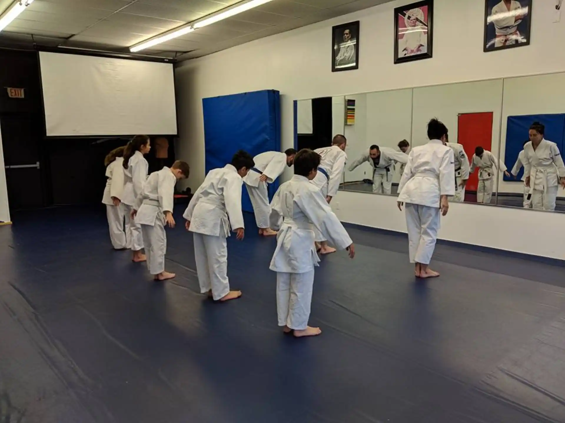 a group of people in white karate uniforms in a room with posters on the wall