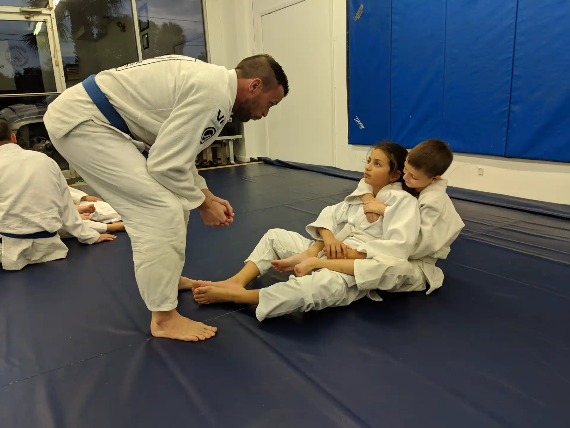 a person in white karate uniform with a group of children in white robes