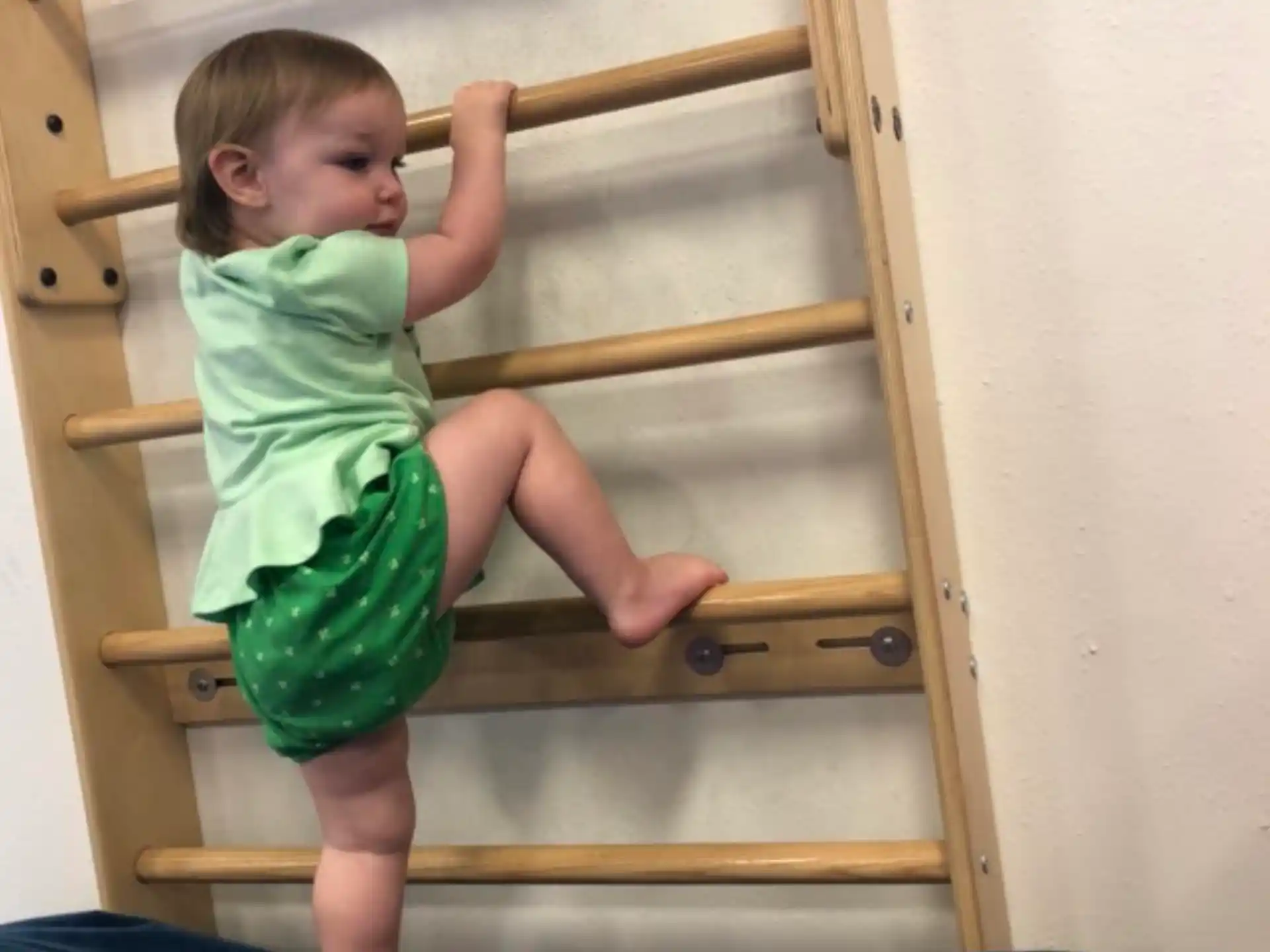 a baby climbing on a wooden structure