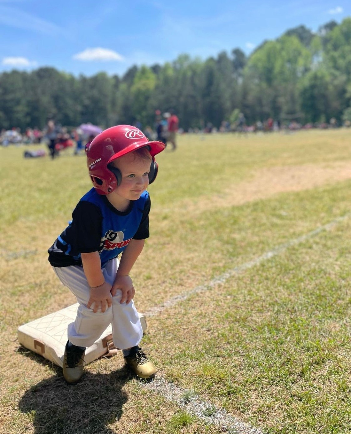 a little boy wearing a red helmet and sitting on a white bench