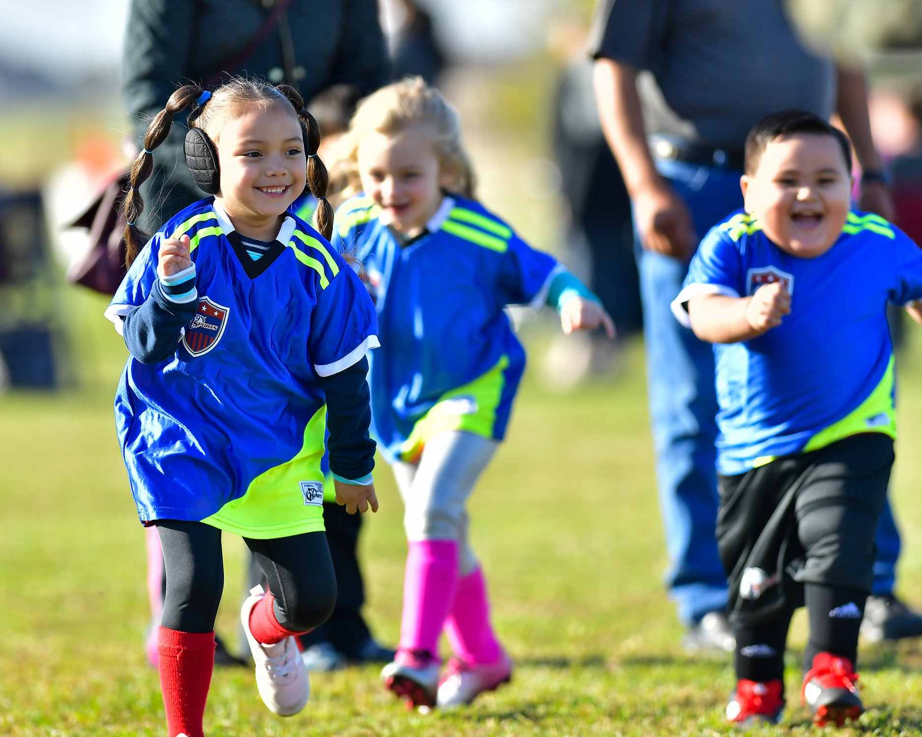 a group of children in blue uniforms running on a field