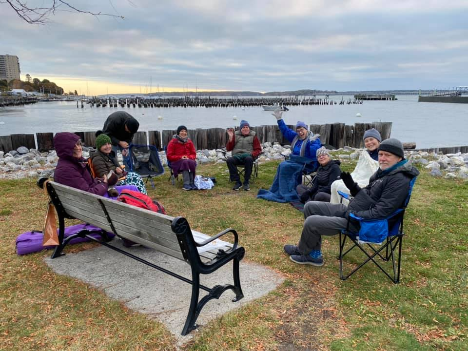 a group of people sitting on a bench by a body of water