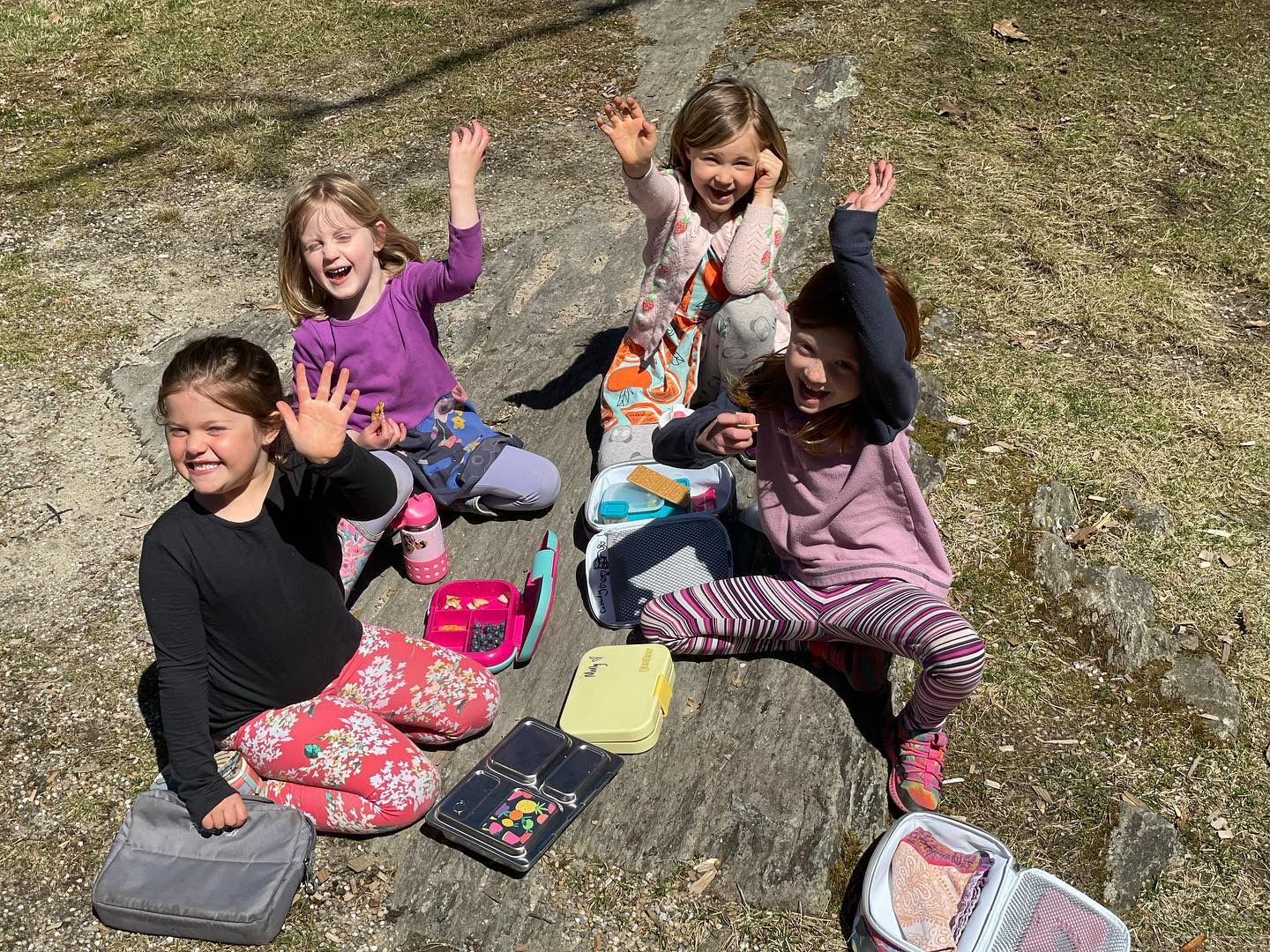 a group of children sitting on the ground with their arms up
