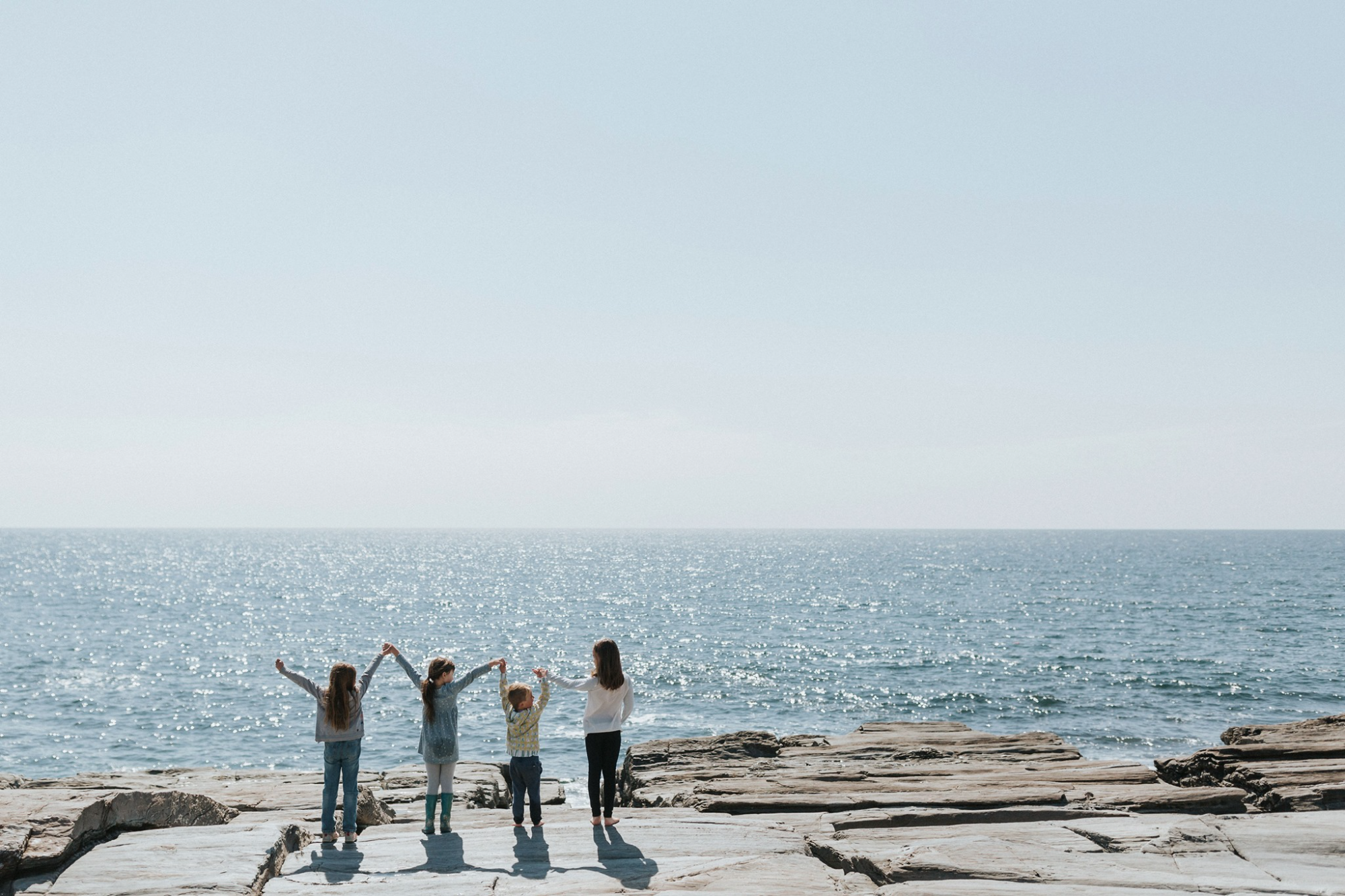 a group of people standing on a rocky beach with their arms raised