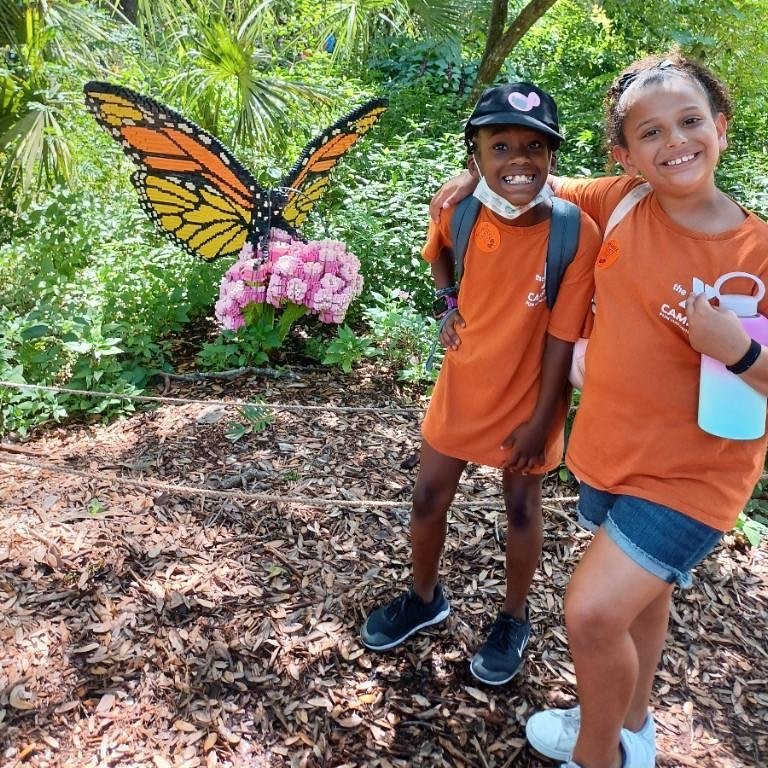a boy and girl posing for a picture with a butterfly on their back