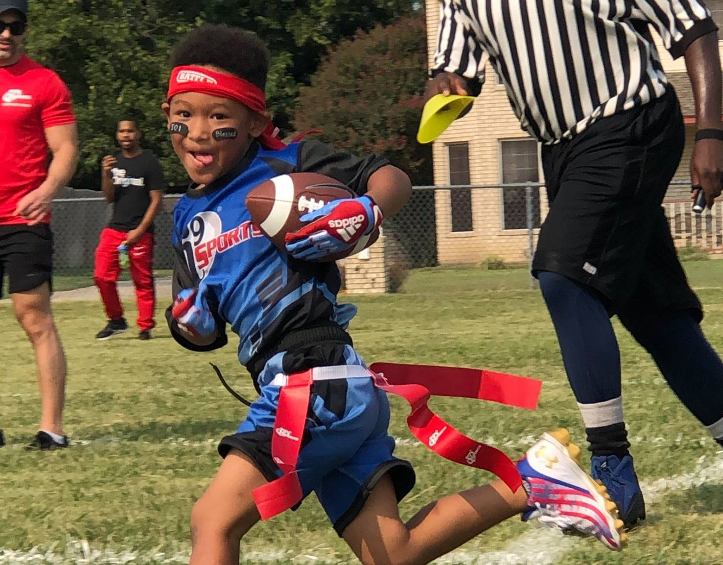 a boy in a blue uniform holding a ball and a yellow frisbee