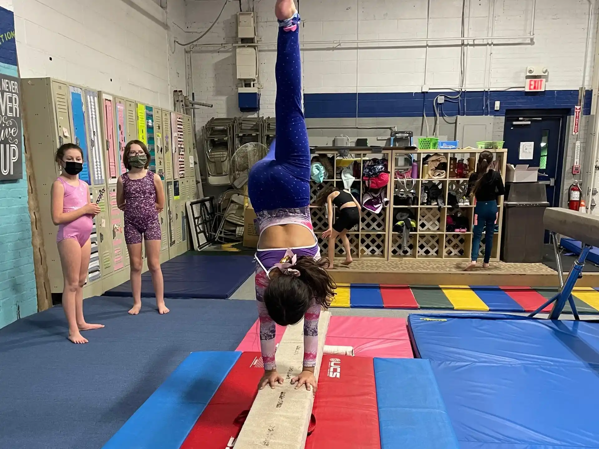 a girl doing a handstand on a mat in a gym