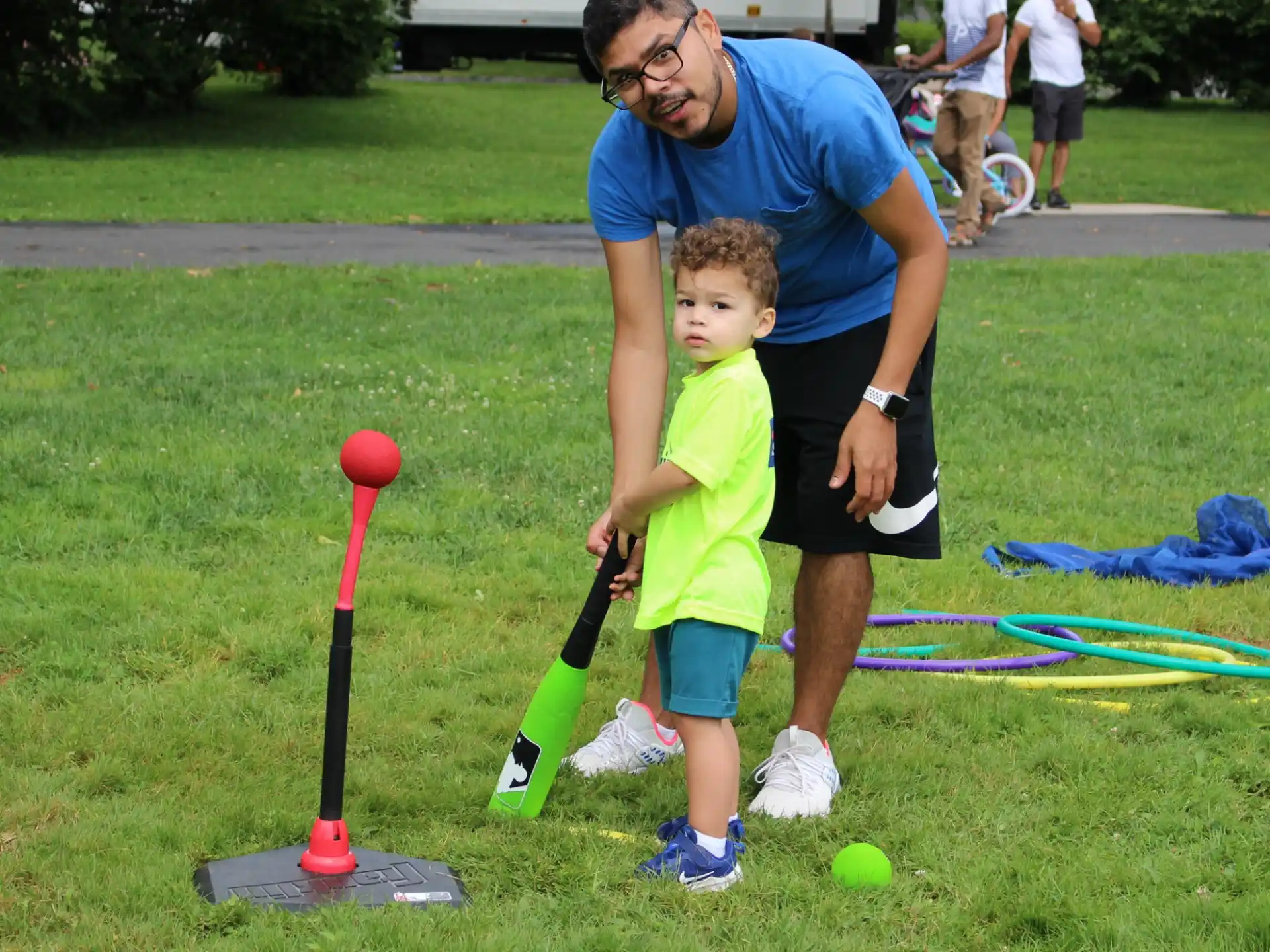 a person and a boy playing tee ball