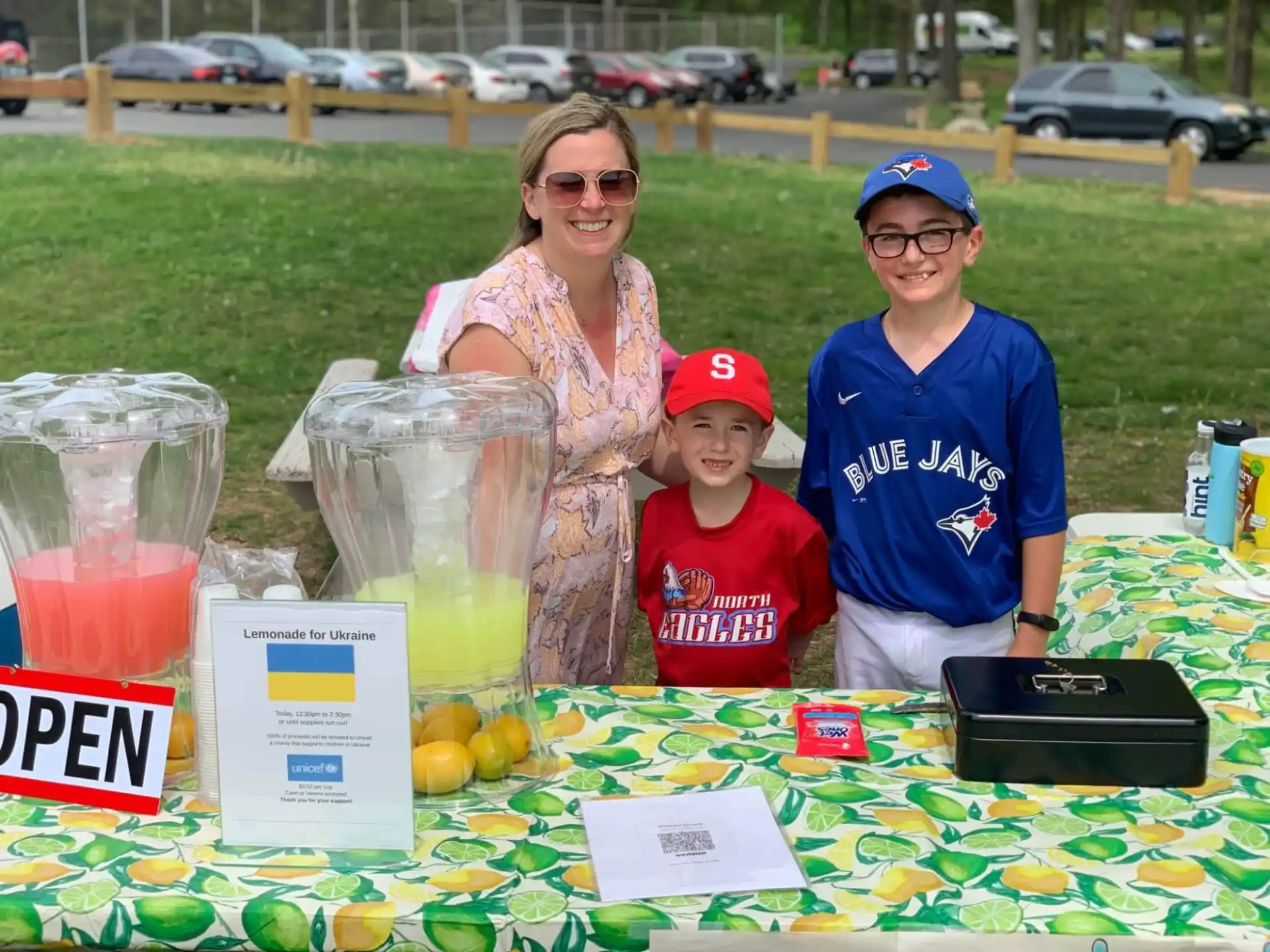 a group of people standing next to a table with fruit and drinks