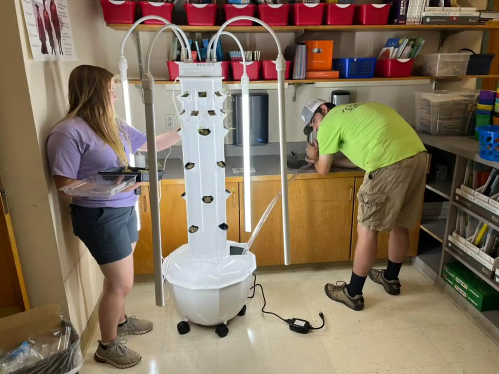 a man and a woman working in a room with shelves and a white machine
