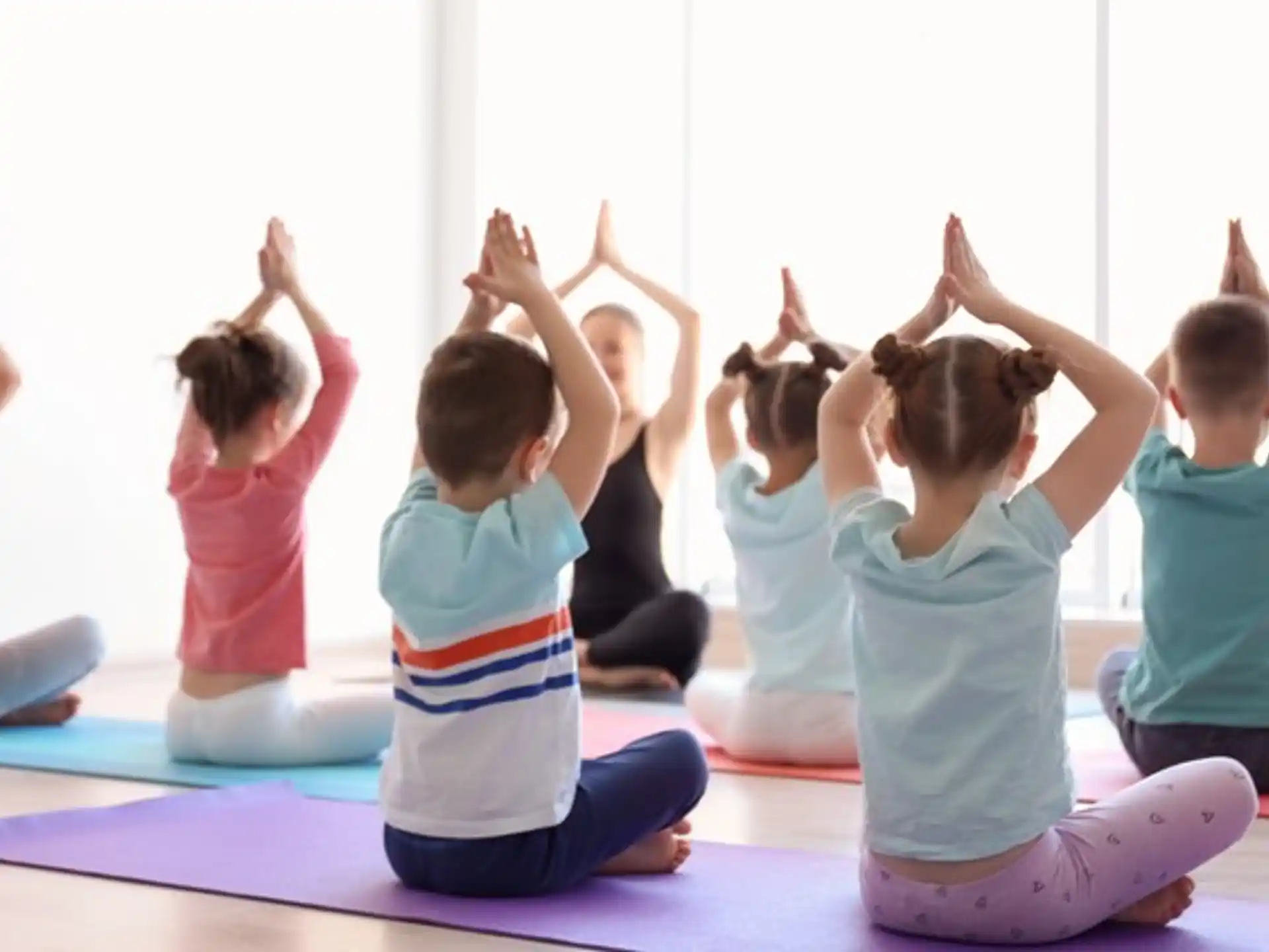 a group of children sitting on the floor with their hands up