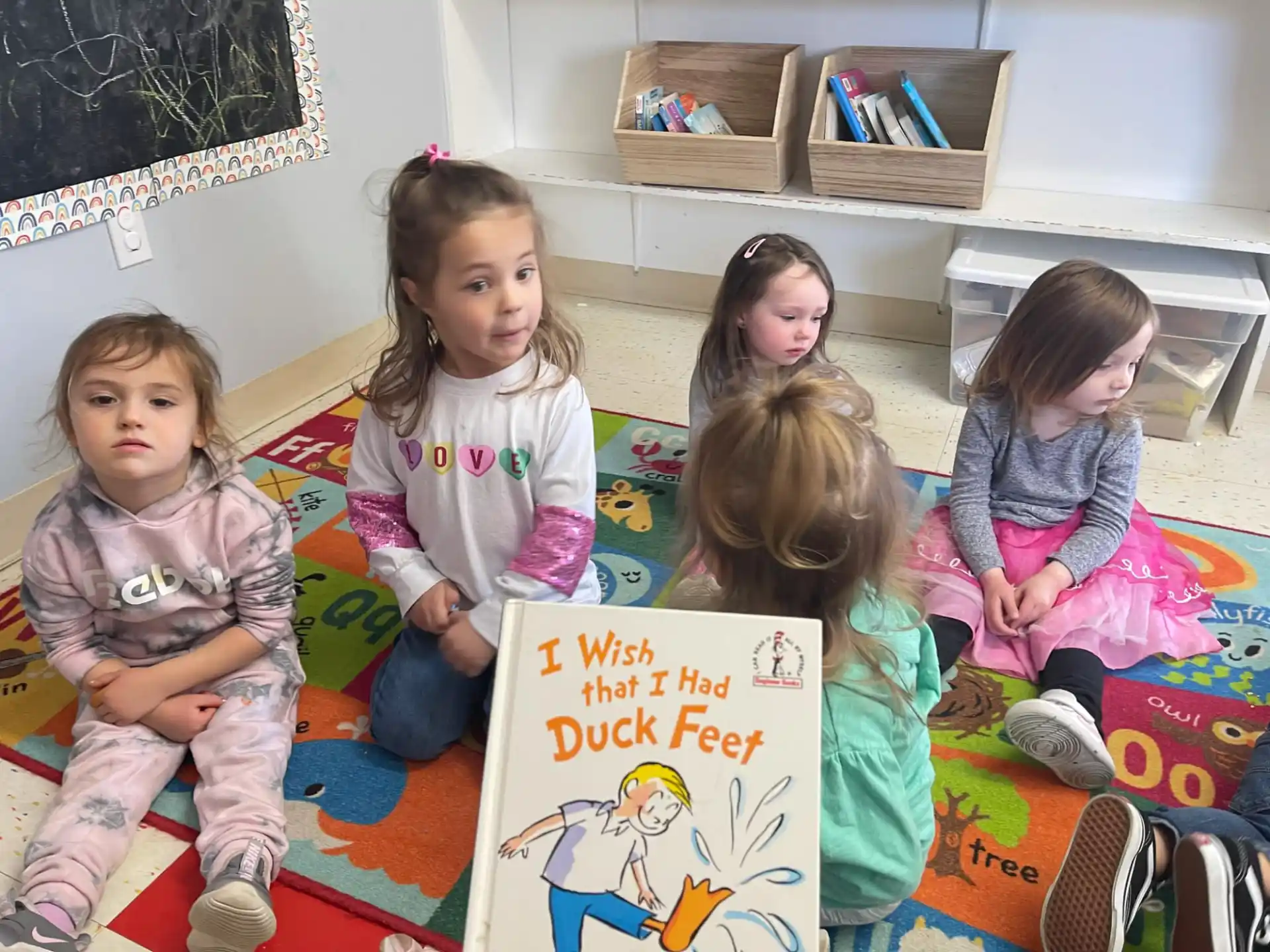 a group of children sitting on a bed holding a sign