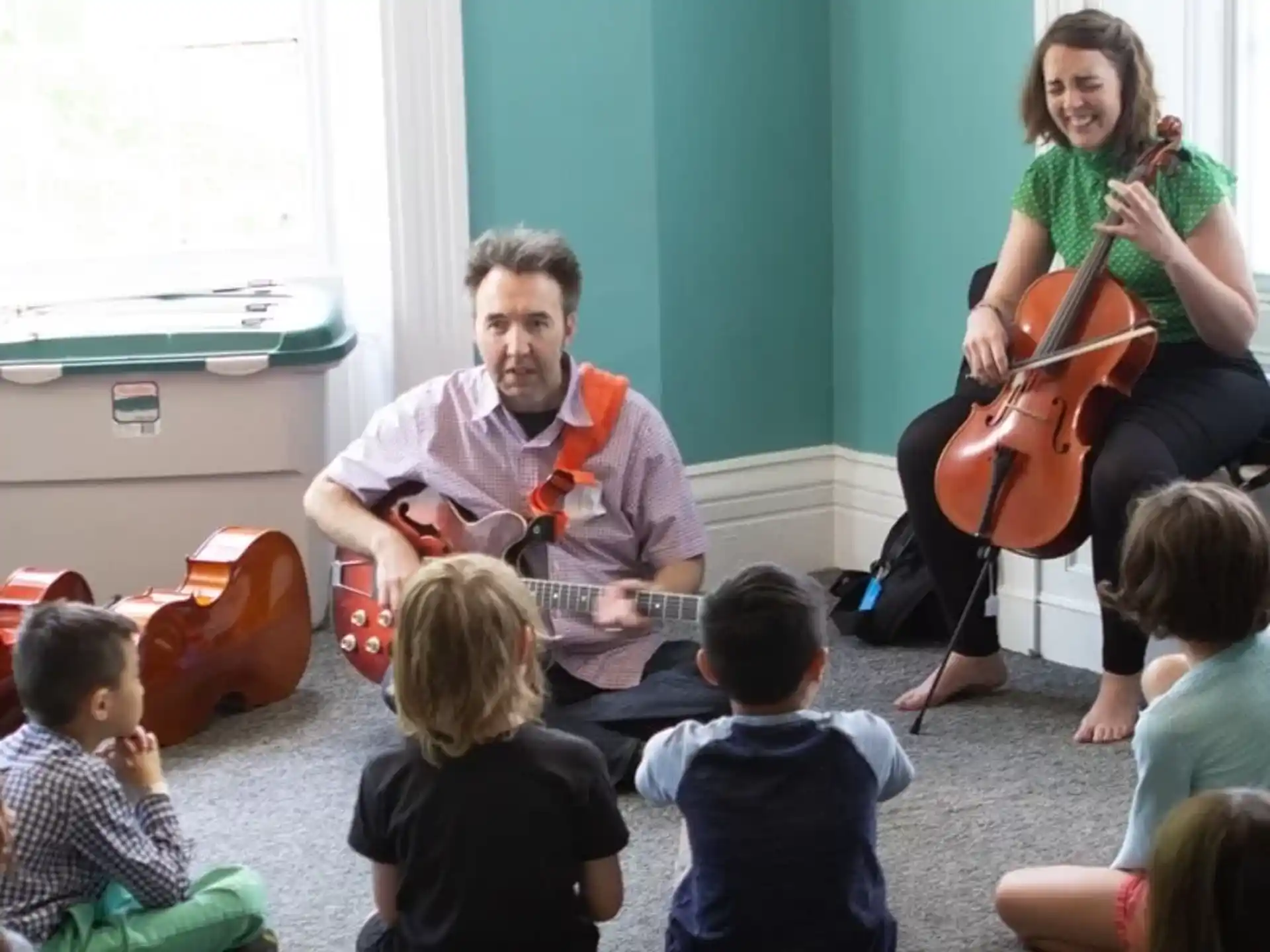 a man and woman playing the violin with children sitting in the front