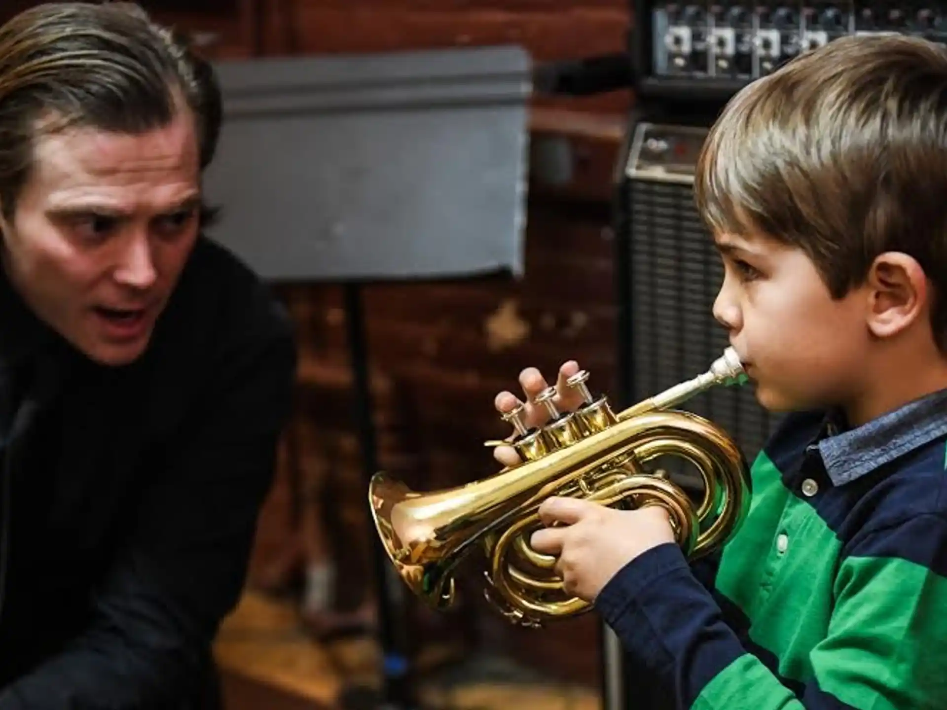 a person playing a brass instrument next to a boy