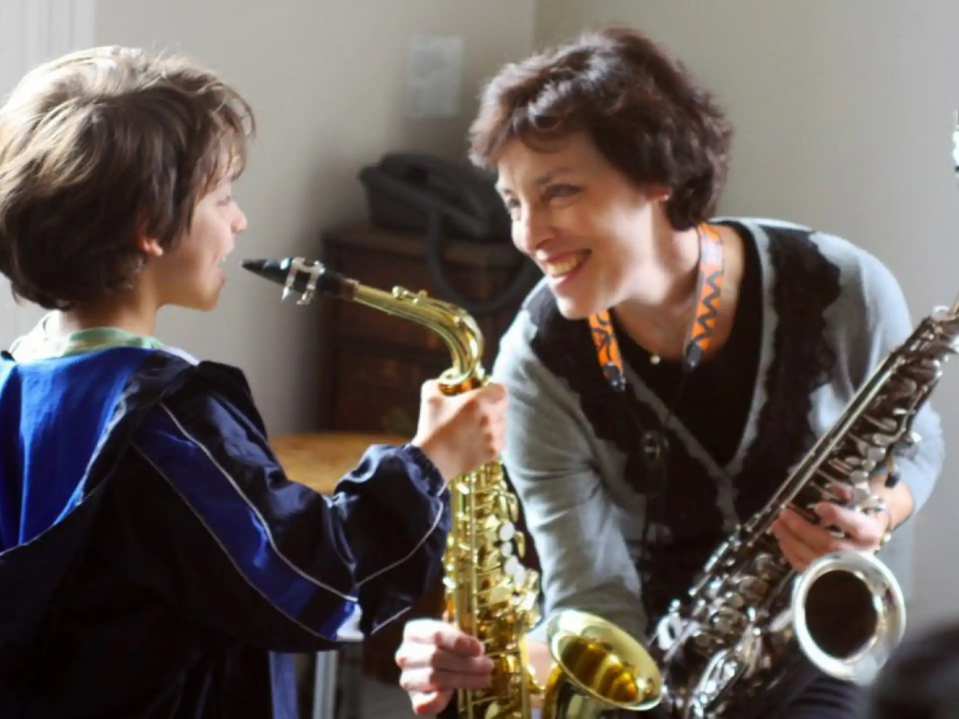 a person playing a saxophone next to a boy playing a saxophone