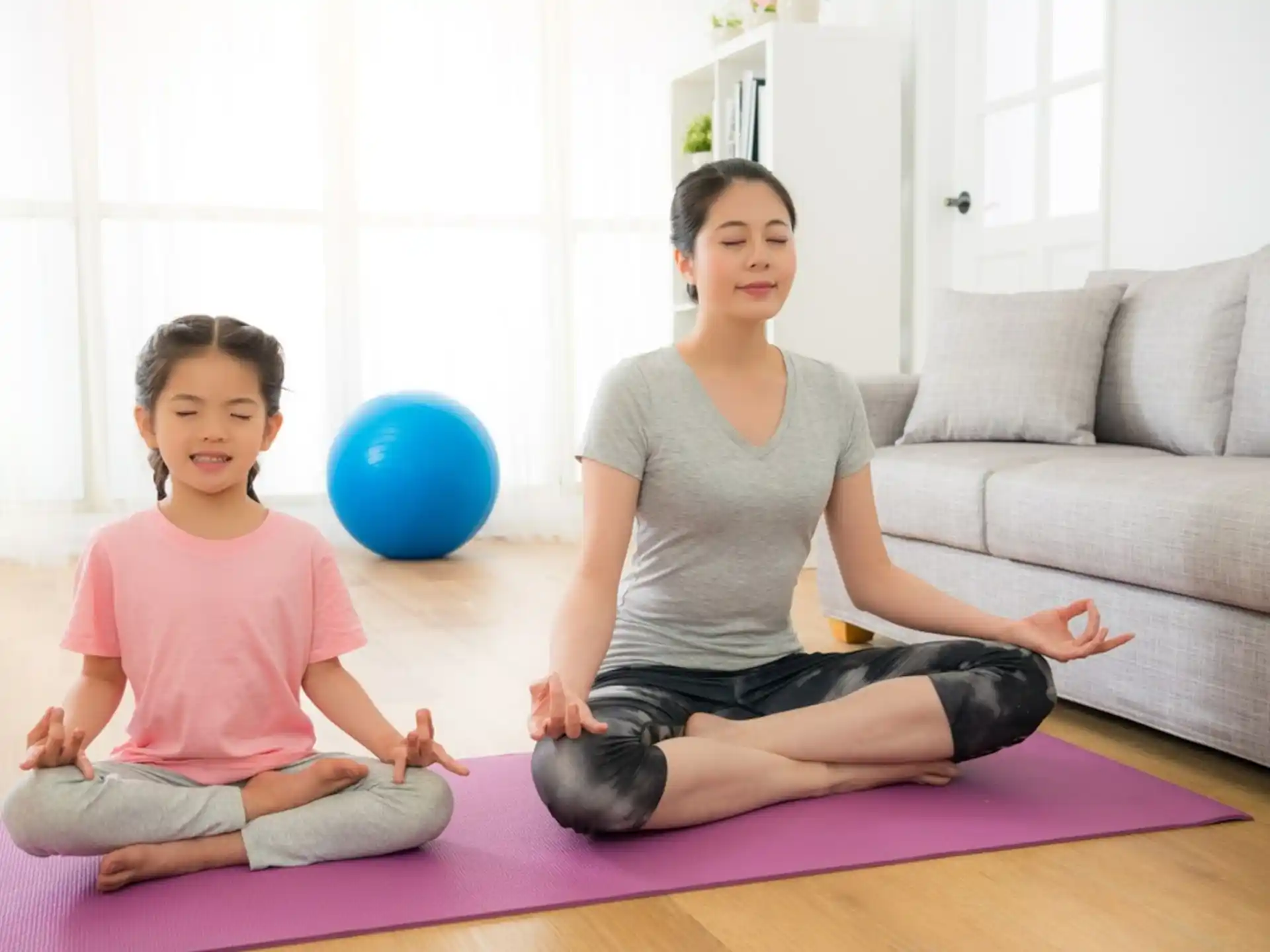 a person and a child sitting on the floor with a blue ball