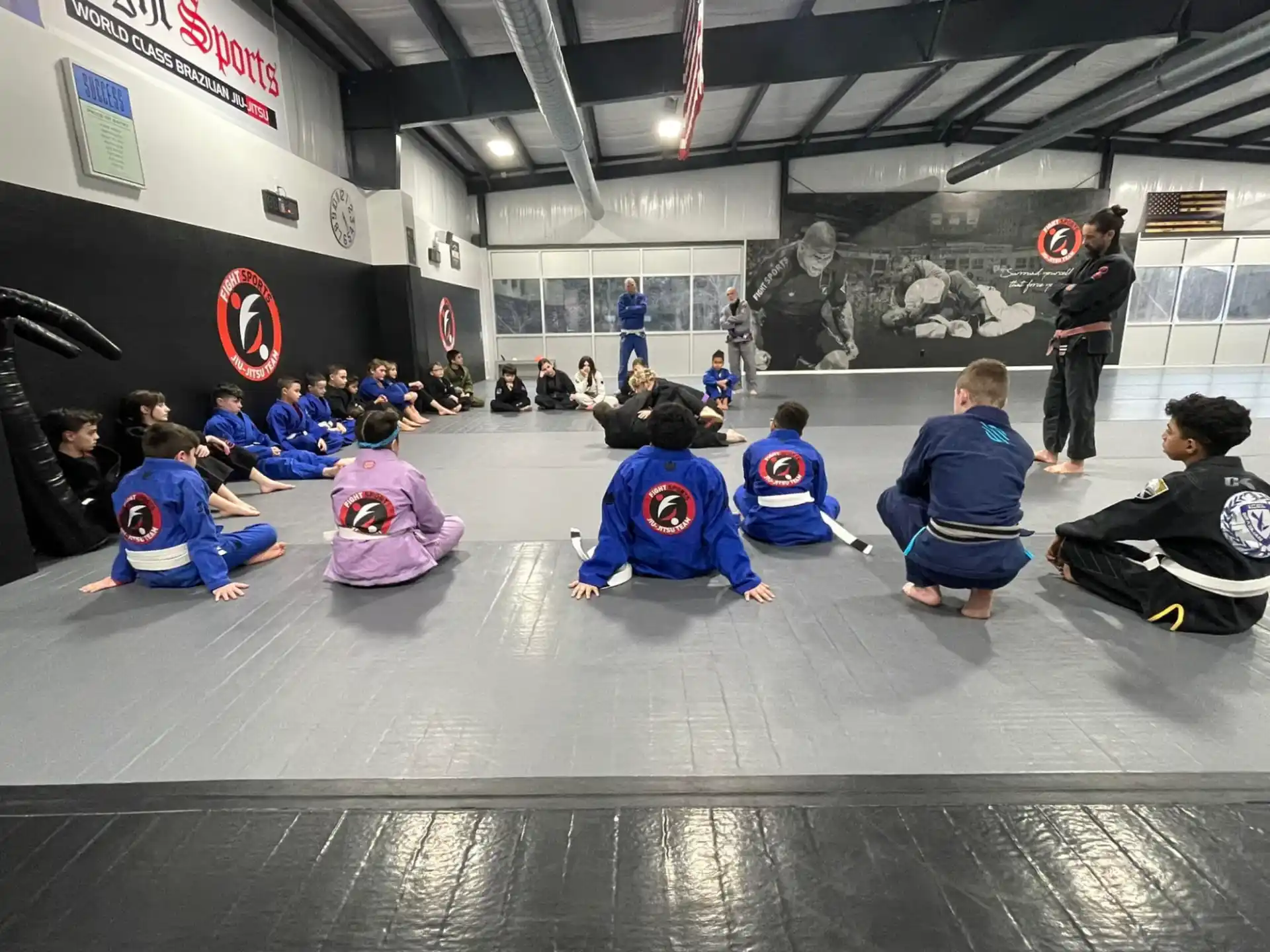 a group of people kneeling on the floor in a room with a person standing and a person standing